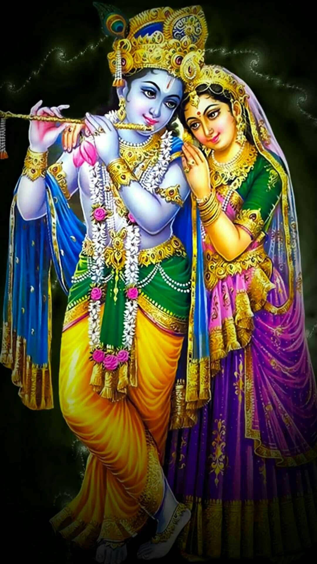 radha krishna HD 桌布 壁紙 — 神聖人物克里希納和拉達裝飾著鮮豔的金色珠寶和色彩繽紛的傳統服飾，在黑暗神秘的背景下分享親密時刻。