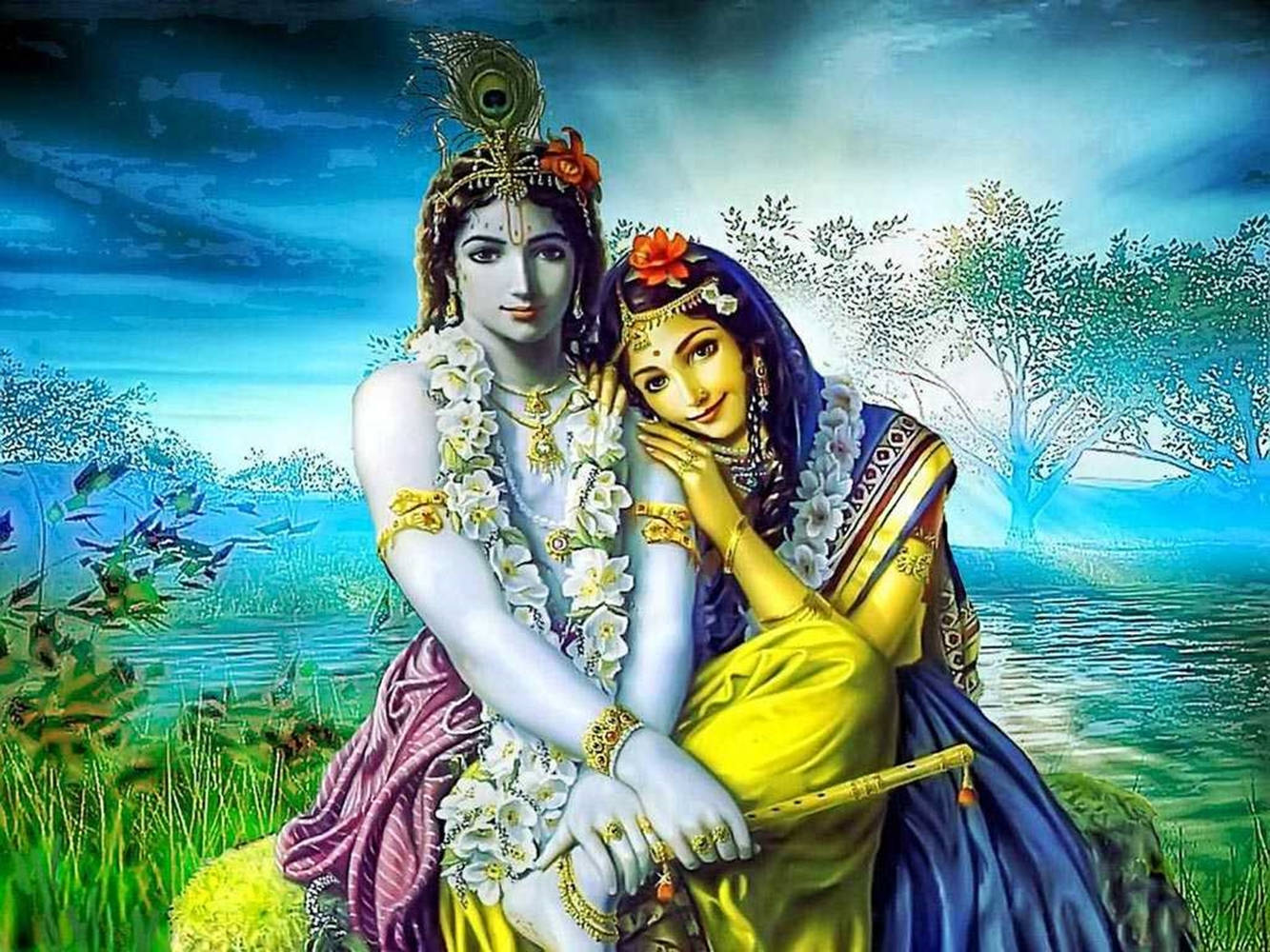 Indian 桌布 壁紙 — 神聖情侶克里希納和拉妲親密地坐在寧靜的湖邊，背景是戲劇性的藍天，點綴著盛開的樹木和茂密的綠植。