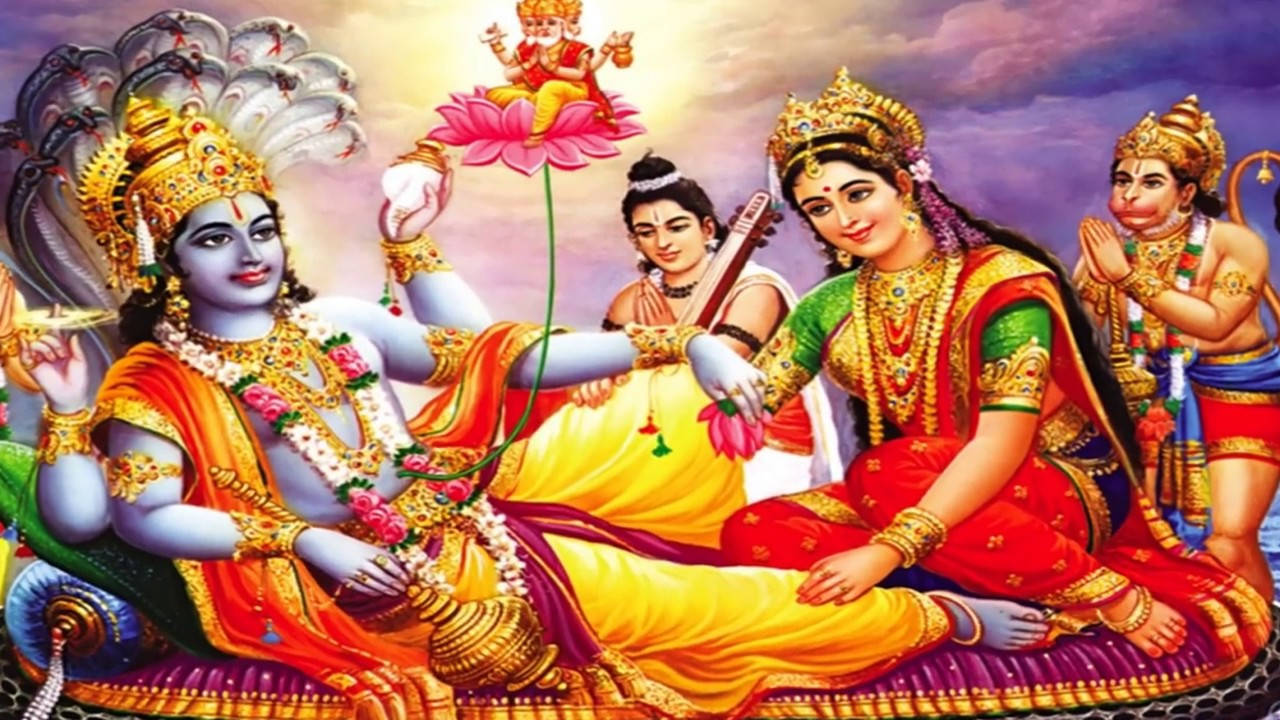 Indian 桌布 壁紙 — 神聖的印度教神祇克里希納和拉達身著華麗金色服飾，與侍從和一位兒童神一同坐在粉紅蓮花之上。