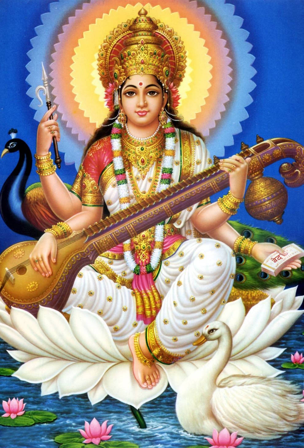 Saraswati Mata 桌布 壁紙 — 神聖的女神薩拉斯瓦蒂優雅地坐在白色蓮花上，手持維納琴和一本書，旁邊有一隻孔雀和一隻天鵝。