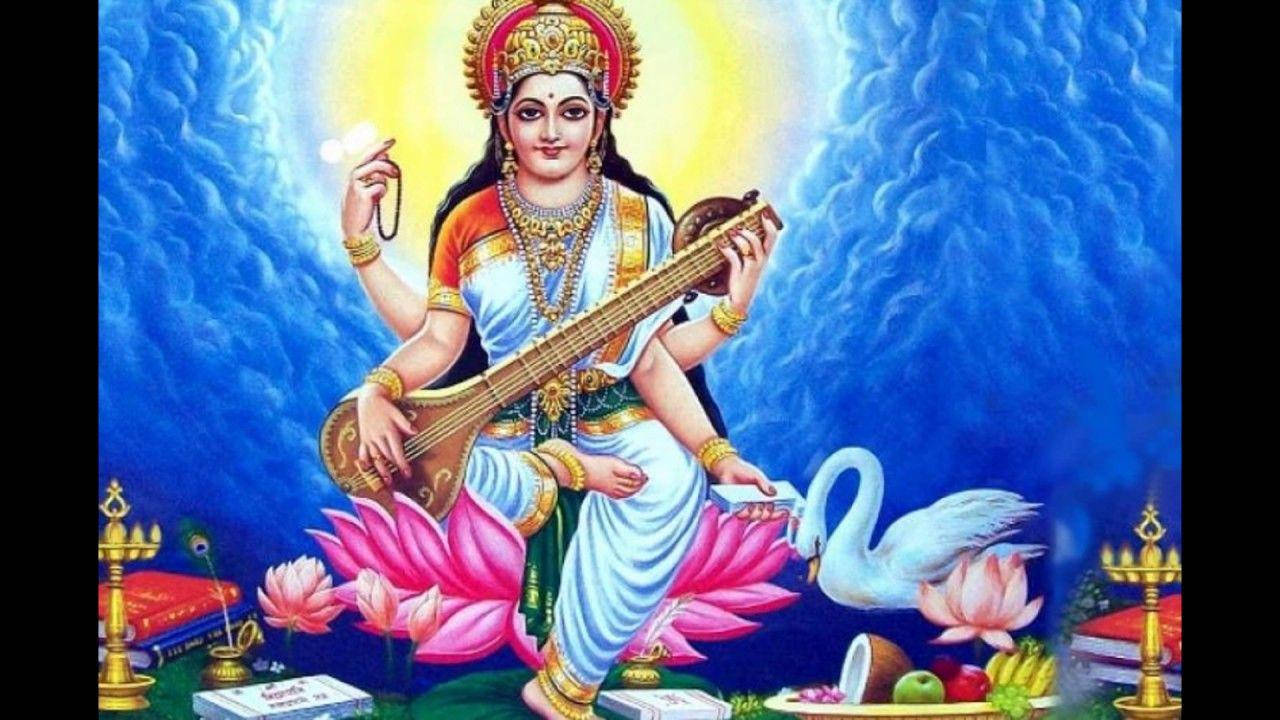 Saraswati Mata 桌布 壁紙 — 神聖的女神薩拉斯瓦蒂優雅地坐在粉紅色的蓮花上，手持維納琴，身旁有一隻天鵝，背景是燦爛的藍色。