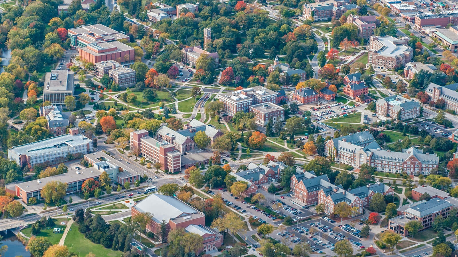 Michigan 桌布 壁紙 — 秋季大學校園的鳥瞰圖，紅磚建築被色彩繽紛的樹葉和蜿蜒小徑環繞。