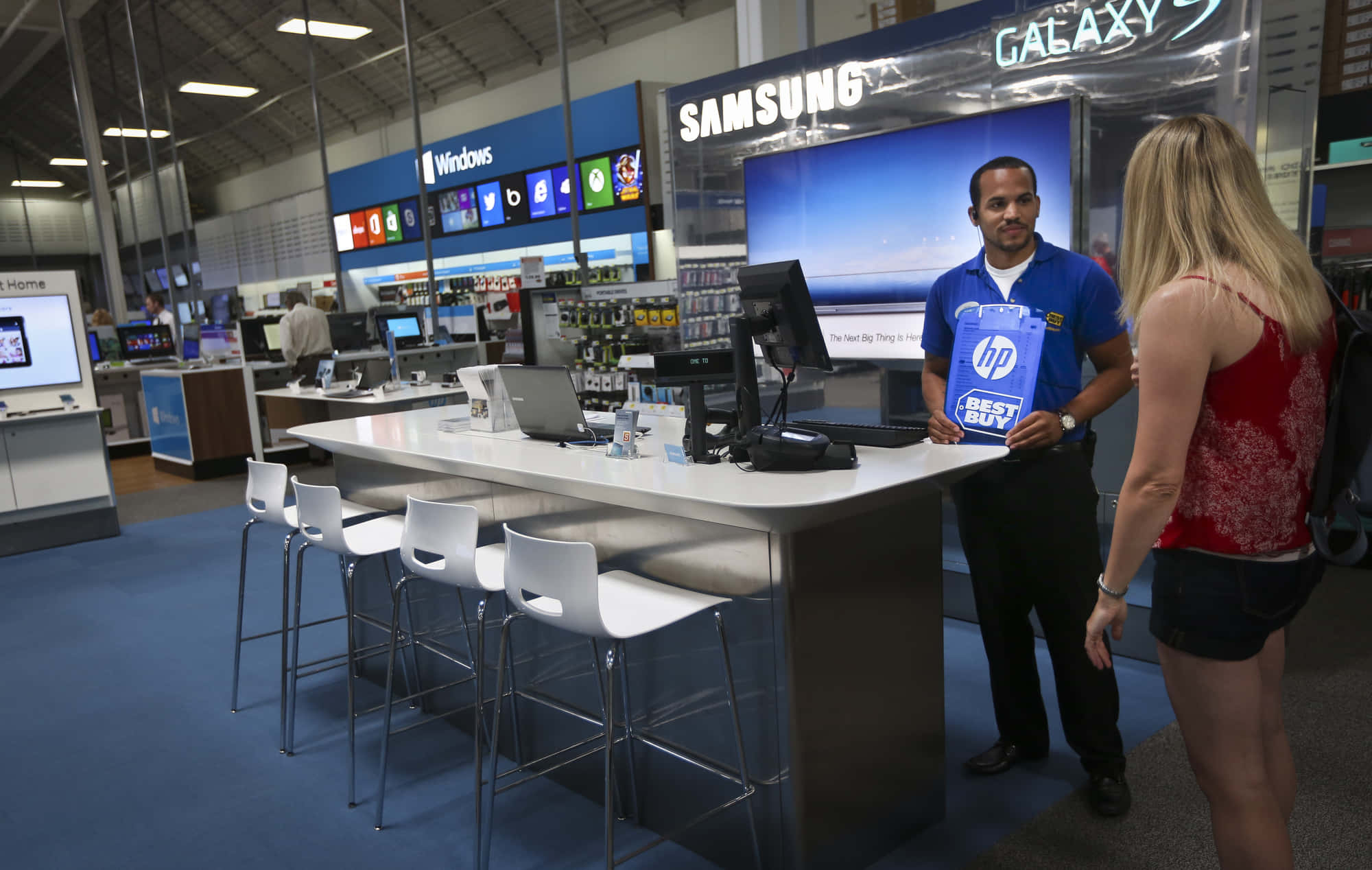 Best Buy 桌布 壁紙 — 科技店的銷售員在Samsung Galaxy顯示屏附近向顧客展示一個HP Best Buy袋。