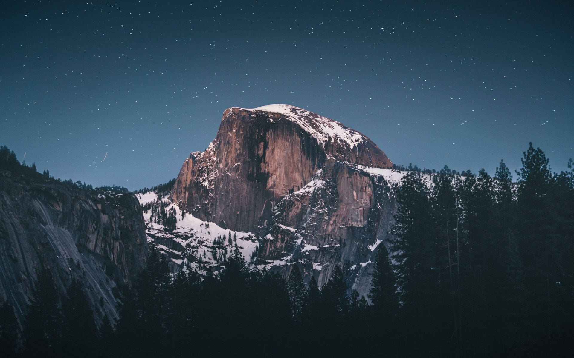 山景 桌布 壁紙 — 積雪的半圓頂在繁星點點的夜空下巍然聳立，周圍環繞著深色松樹。