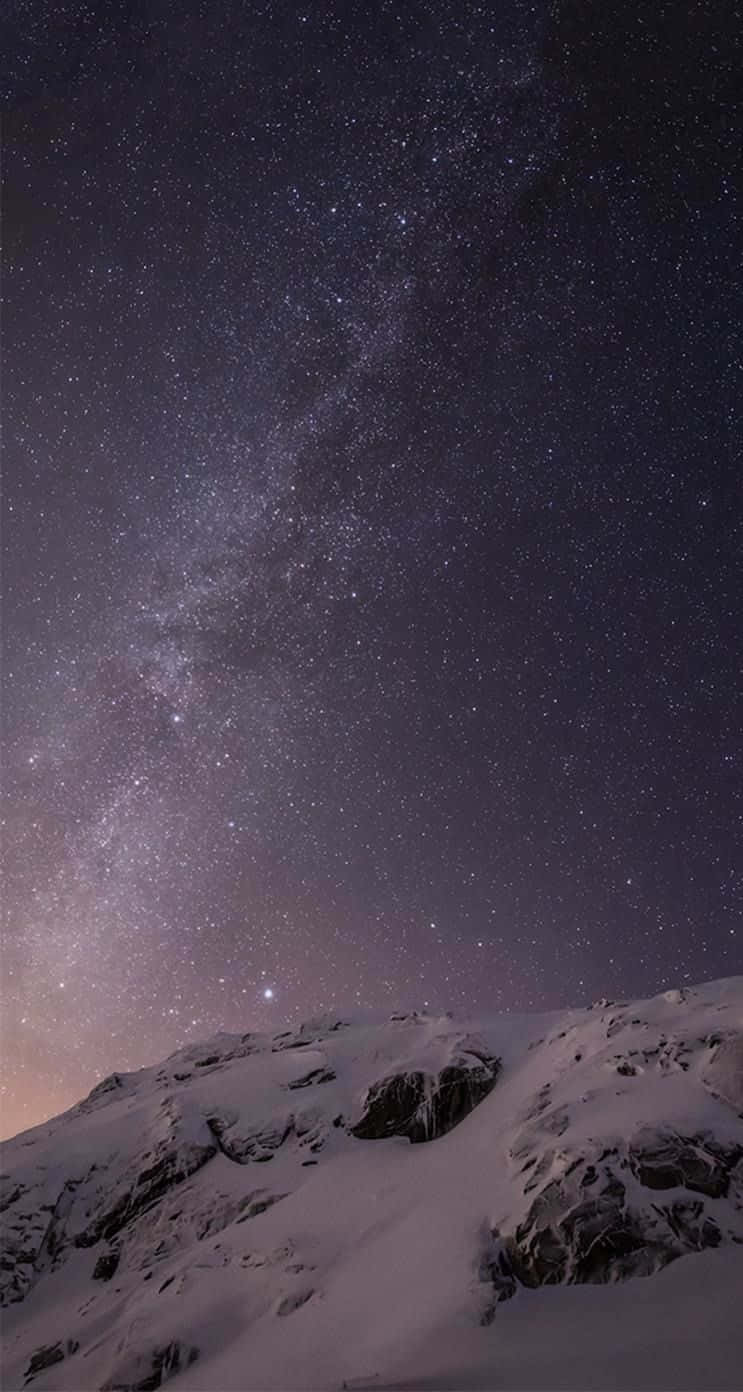iOS 桌布 壁紙 — 積雪的山峰仰望壯麗的星空，銀河拱橋橫跨天際。