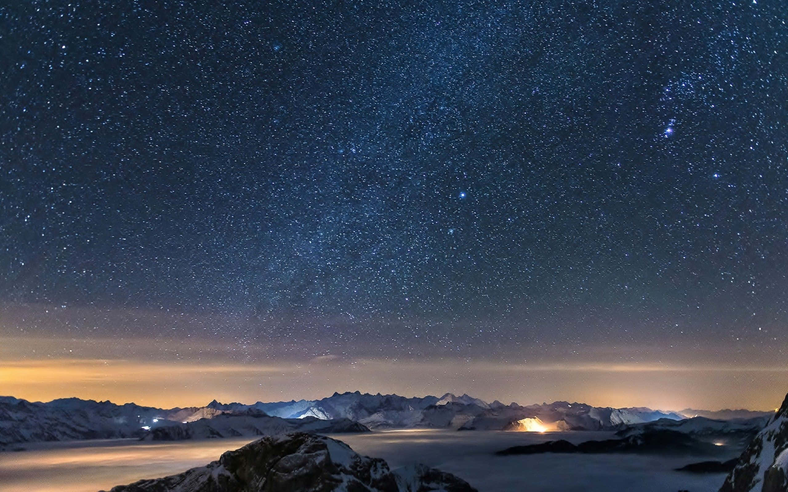 Alps 桌布 壁紙 — 積雪的山峰刺穿星爆天空，下方是雲海，遠處山谷燈光閃爍。