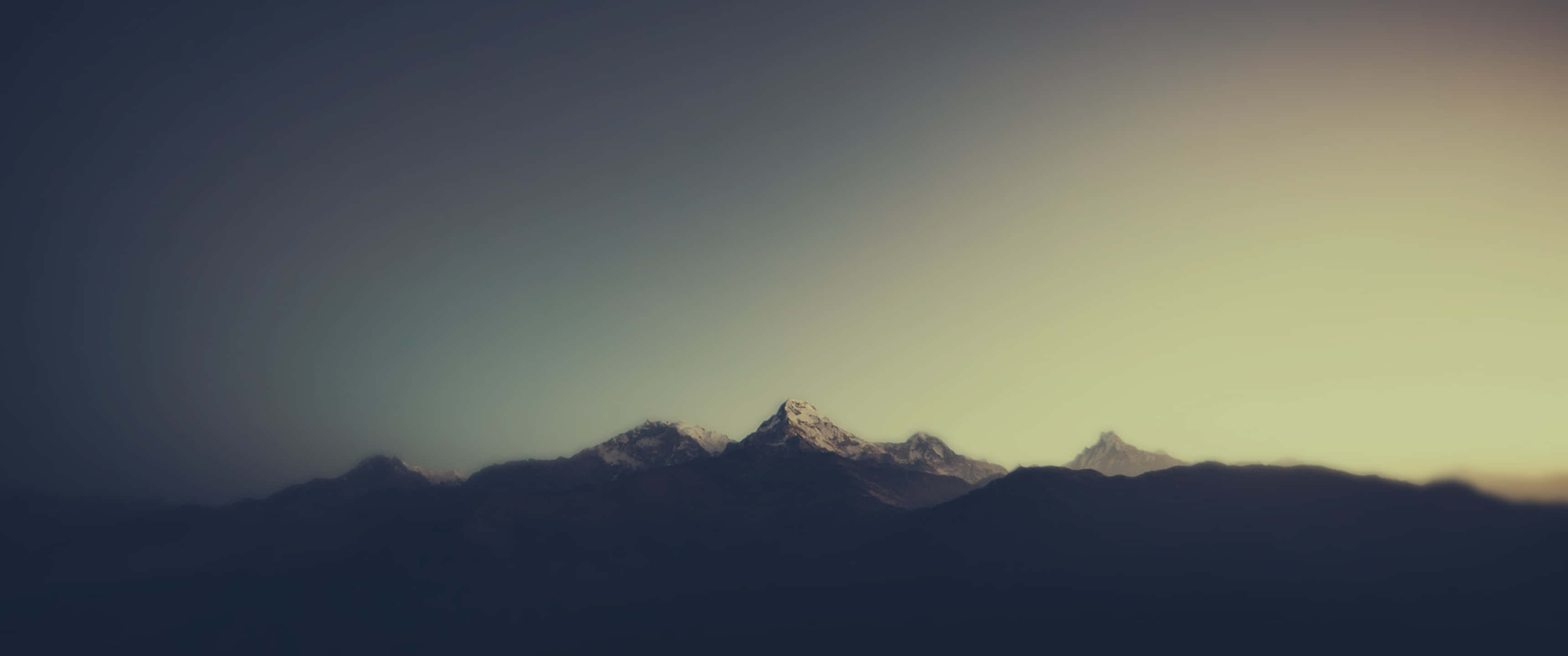 Mountain Aesthetic 桌布 壁紙 — 積雪的山峰剪影在漸層的天空中升起，天空閃耀著日落色調。