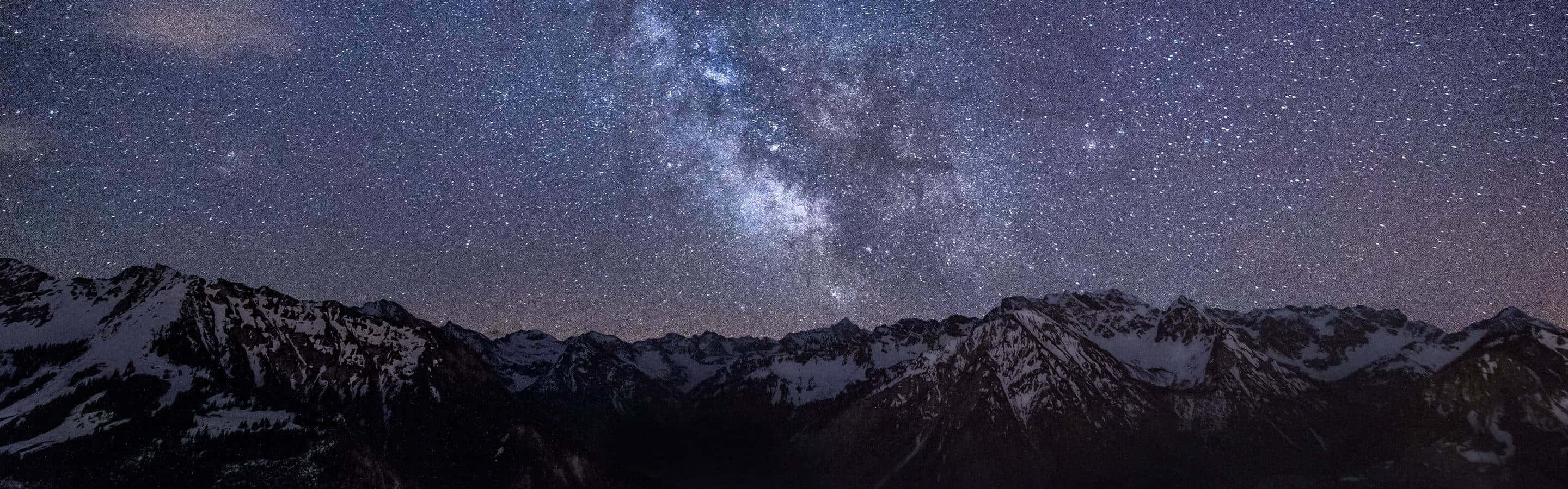高清 桌布 壁紙 — 積雪的山峰在令人嘆為觀止的星空下聳立，銀河在頭頂明亮地閃耀。