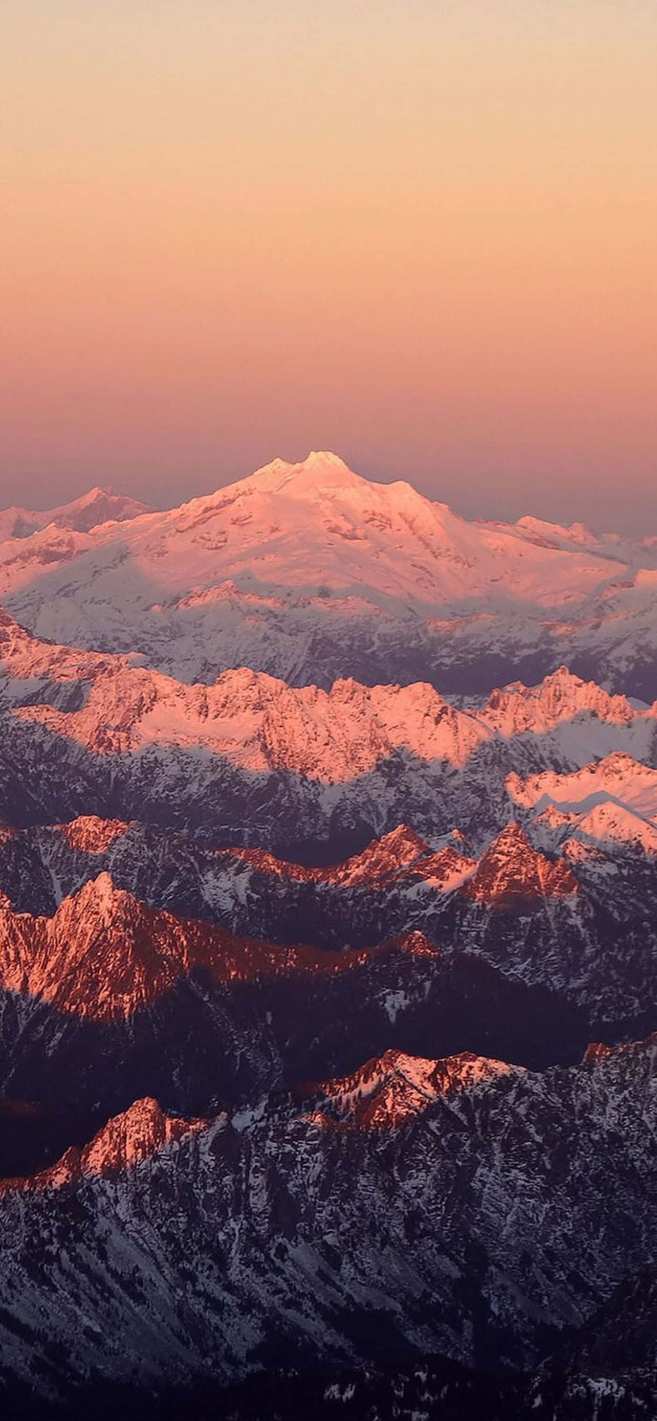 Mountain iPhone 桌布 壁紙 — 積雪的山峰在令人驚嘆的日出中閃耀著溫暖的粉紅色和橙色色調。