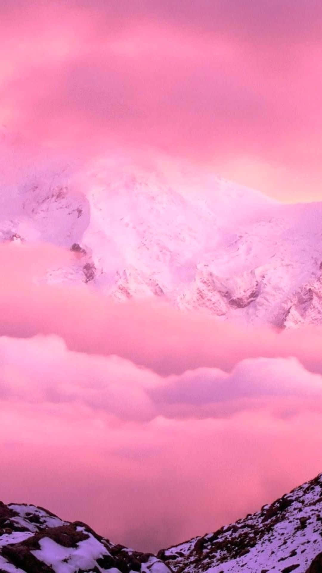 粉紅色 iPhone 桌布 壁紙 — 積雪的山峰在夢幻般的暮色天空下穿透柔軟的粉紅色雲層。