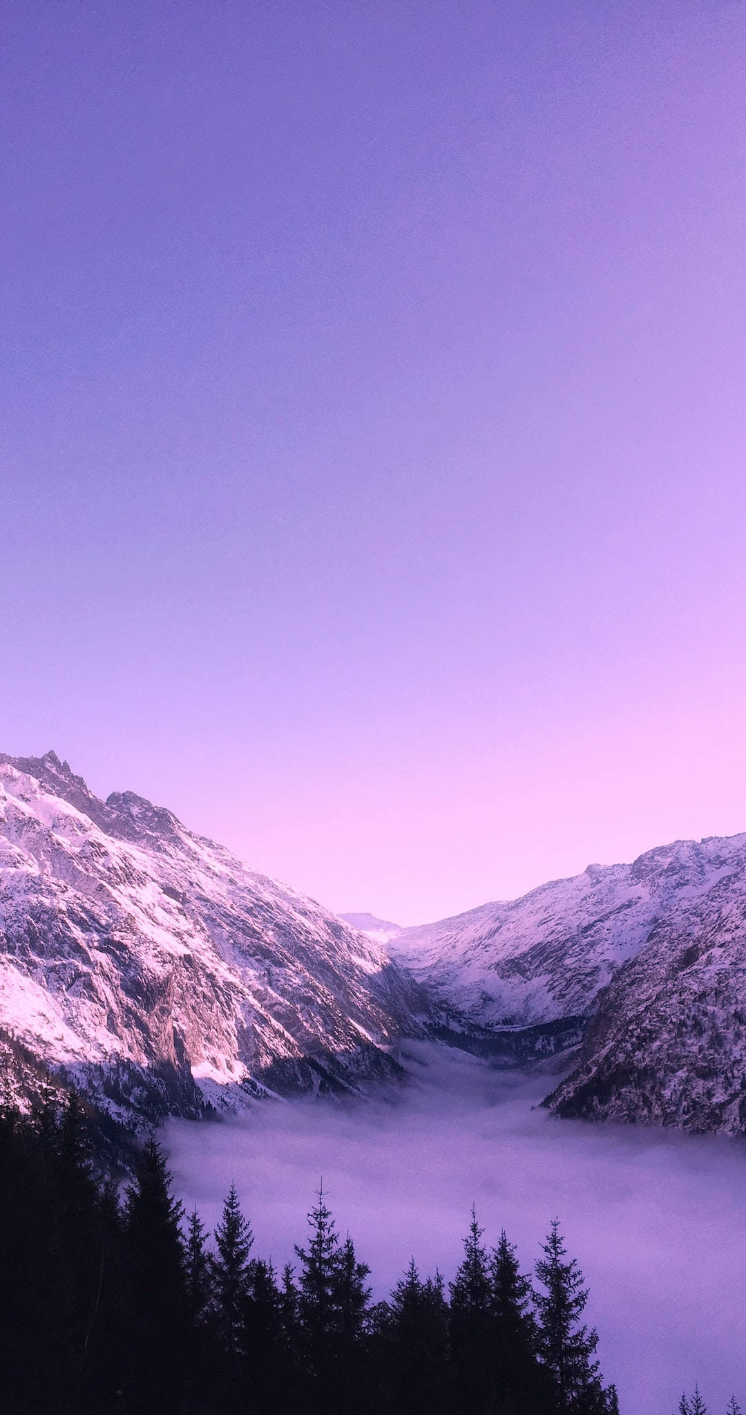 Nature iPhone 桌布 壁紙 — 積雪的山峰在暮色天空下，從紫色霧海中升起。