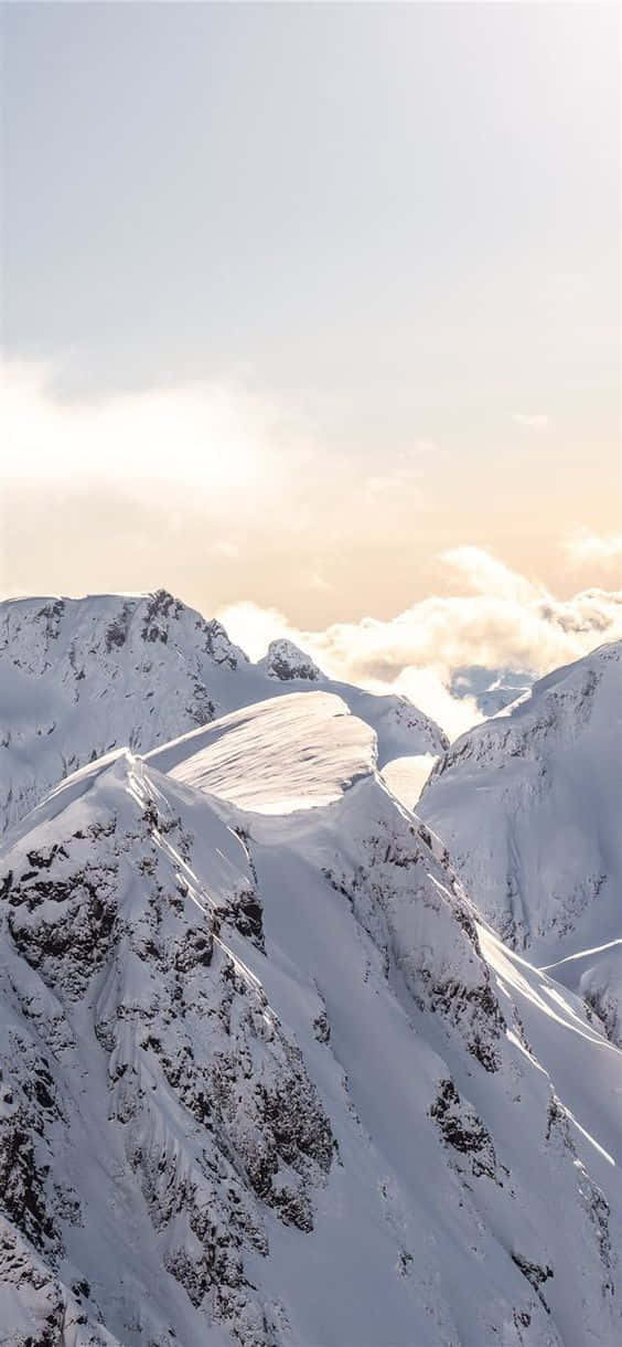積雪的山峰在日出時高聳於雲層之上。 — 雪 壁紙