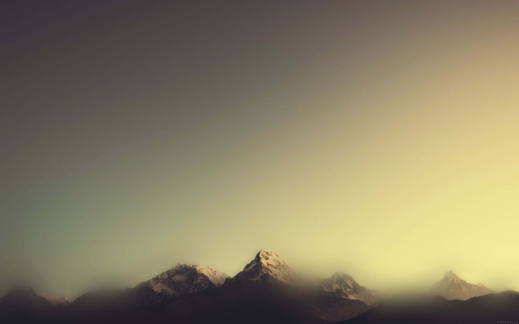 Minimalist Mountain 桌布 壁紙 — 積雪的山峰在漸層的天空下從薄霧中浮現，天空閃耀著溫暖的日落色調。