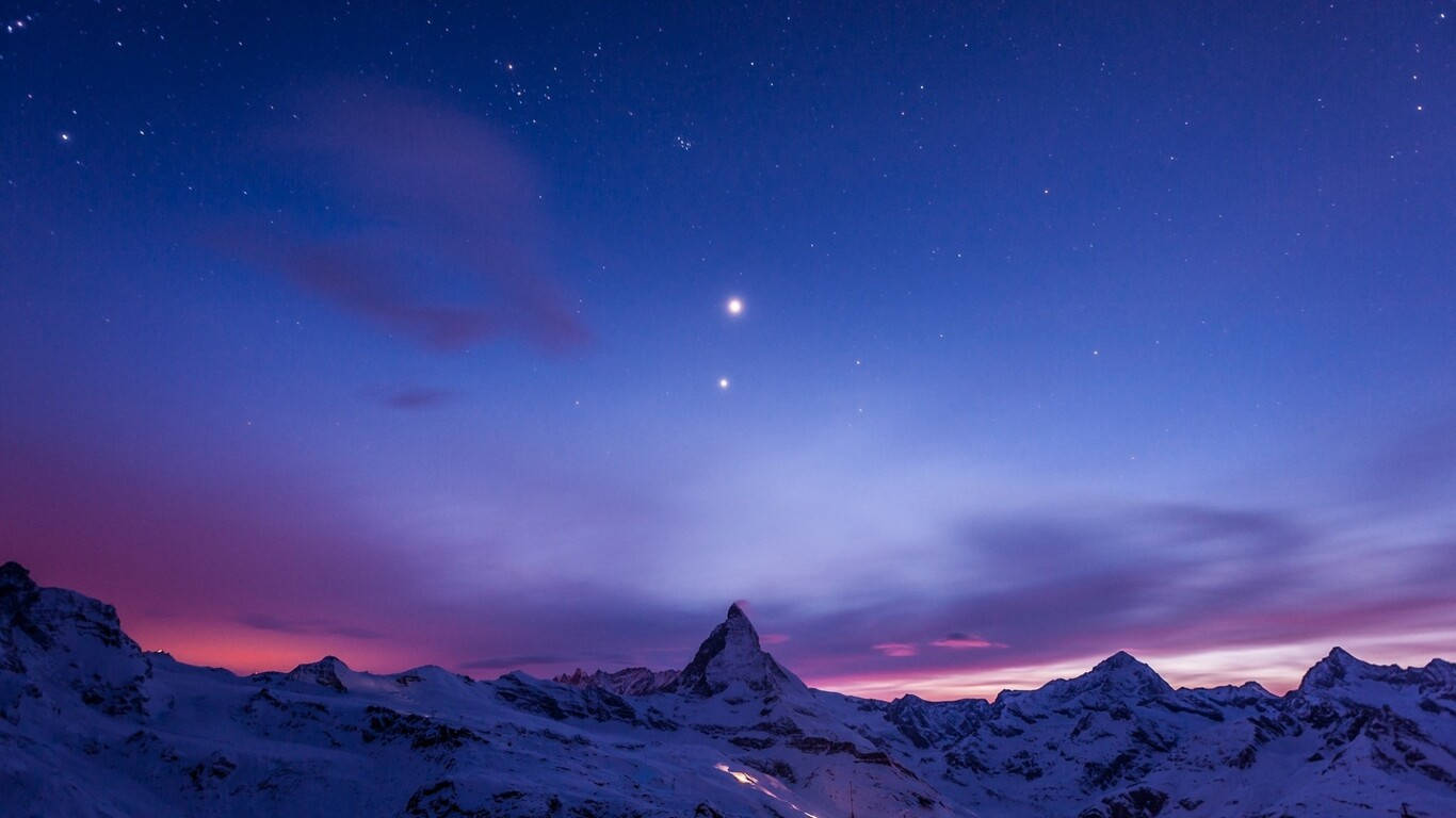 冬天 桌布 壁紙 — 積雪的山峰在紫粉色的星暮天空下聳立。