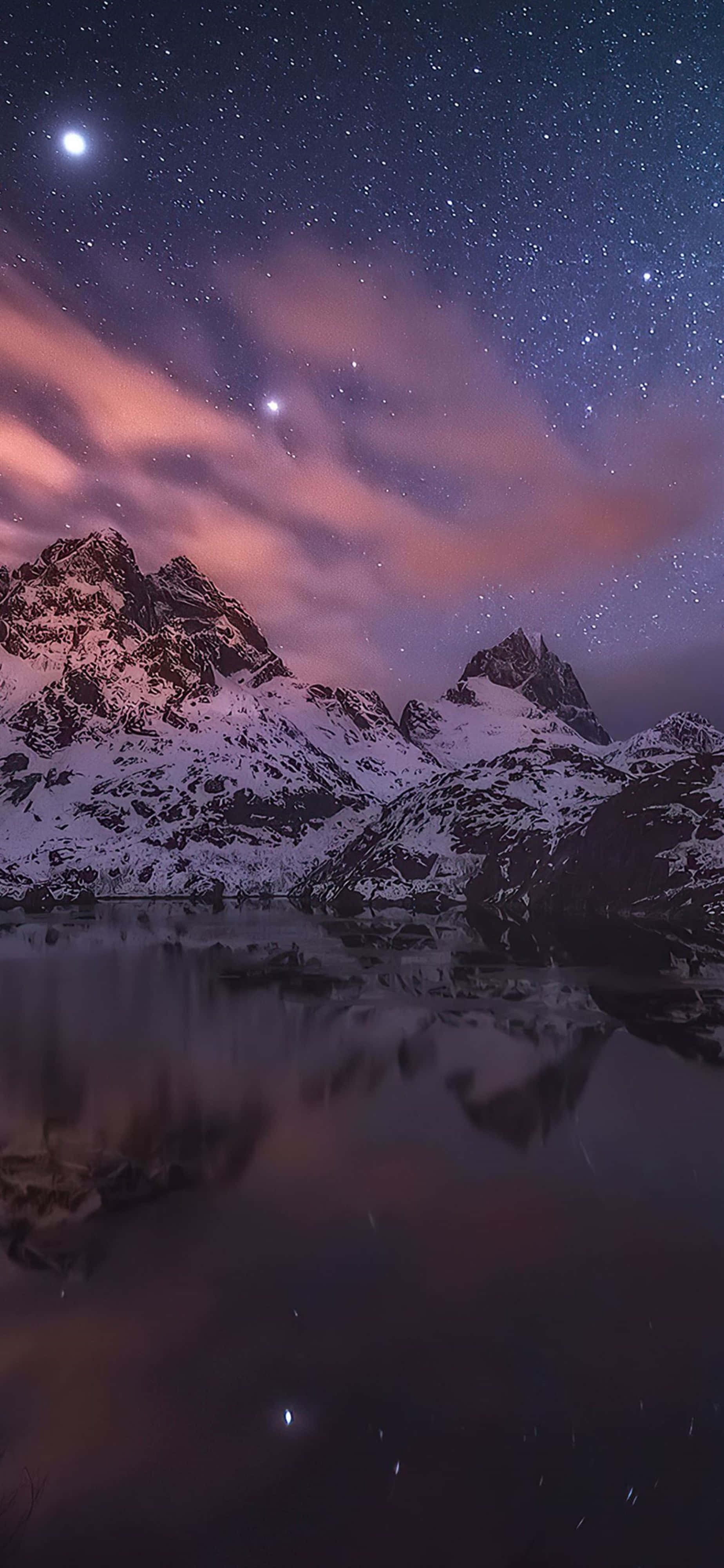 自然 桌布 壁紙 — 積雪的山峰在繁星點點的夜空下倒映，粉紅色的雲朵和一輪明月高懸於平靜的水面之上。