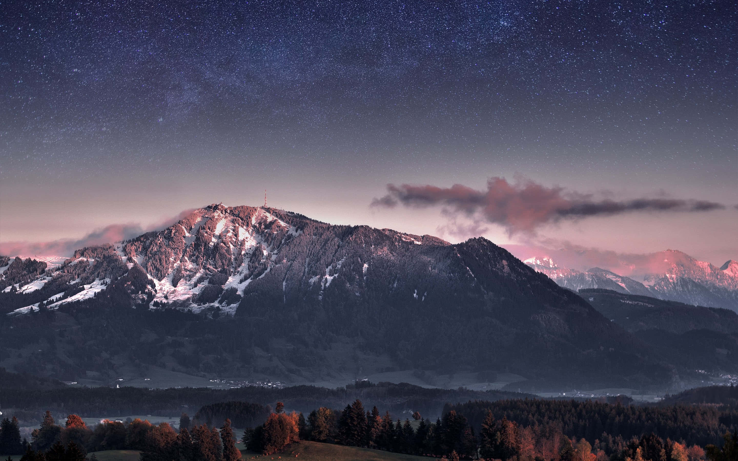 Mountain Landscape 桌布 壁紙 — 積雪的山峰在繁星點點的暮色天空下閃耀，粉紅色的雲朵和遠處的燈光在下方。