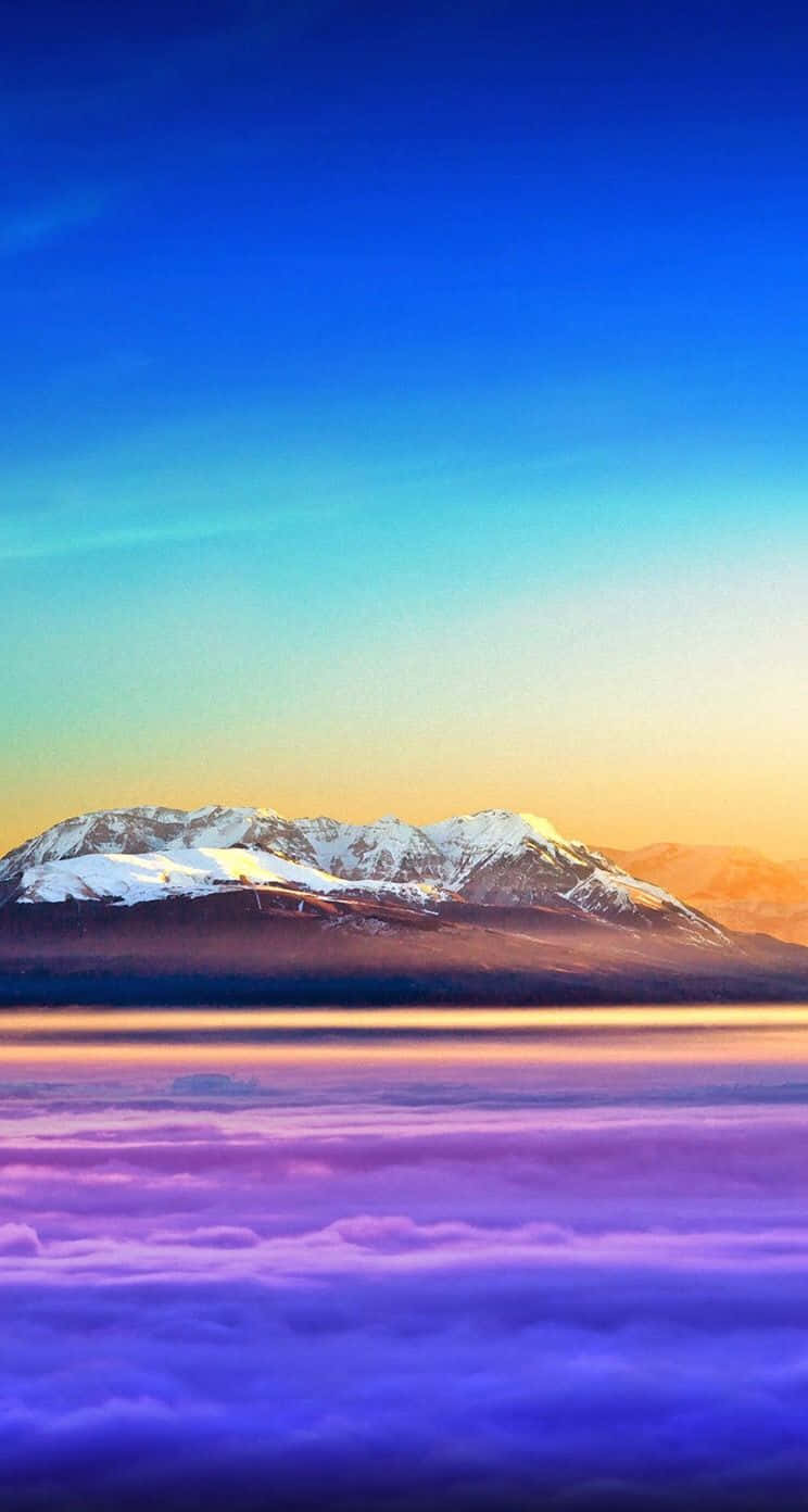 iOS 桌布 壁紙 — 積雪的山峰在藍橙漸變的天空下，從紫色雲海中升起。