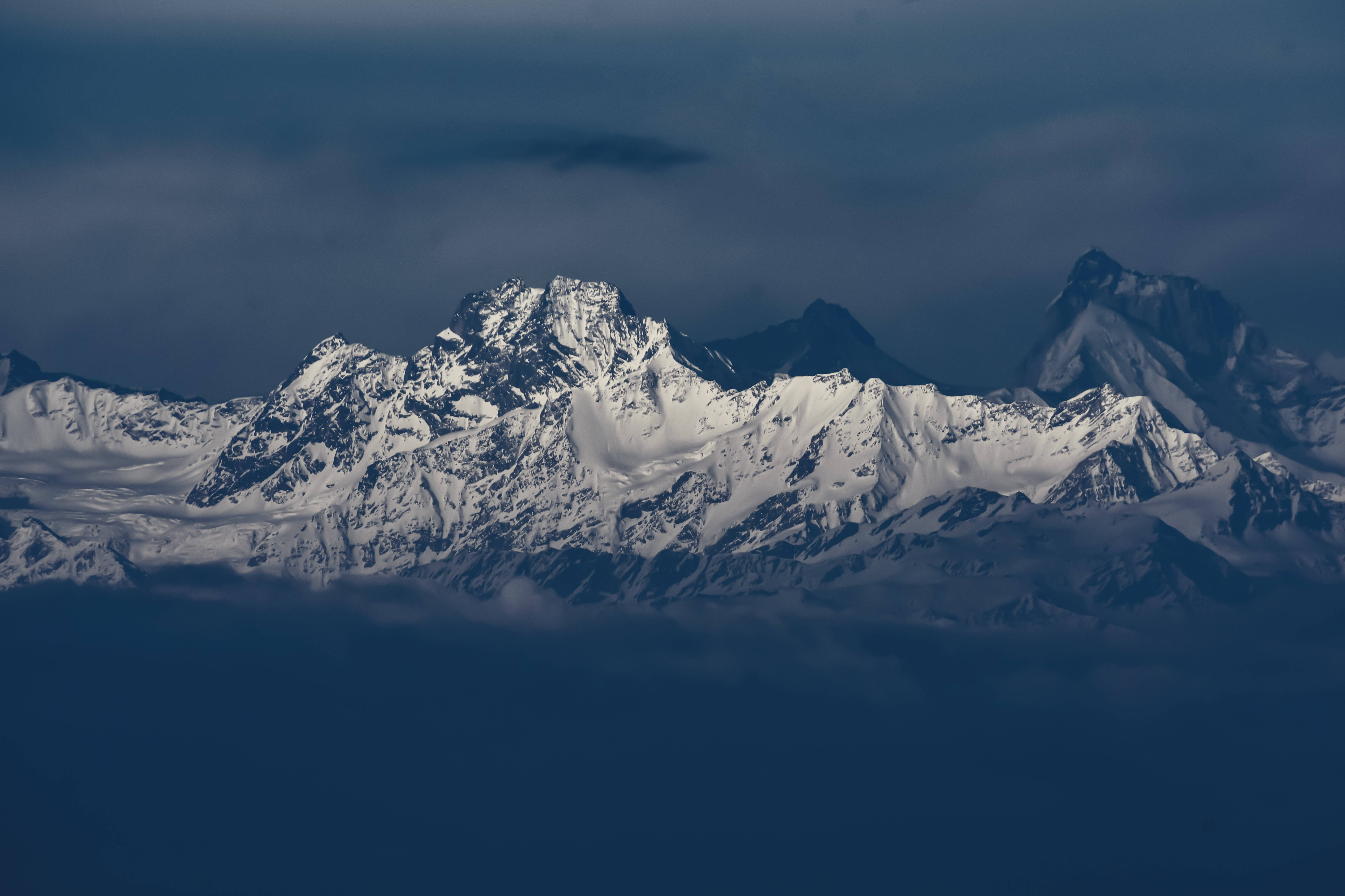 mac 4K 桌布 壁紙 — 積雪的山峰在迷濛的藍色山谷之海上刺穿烏雲。