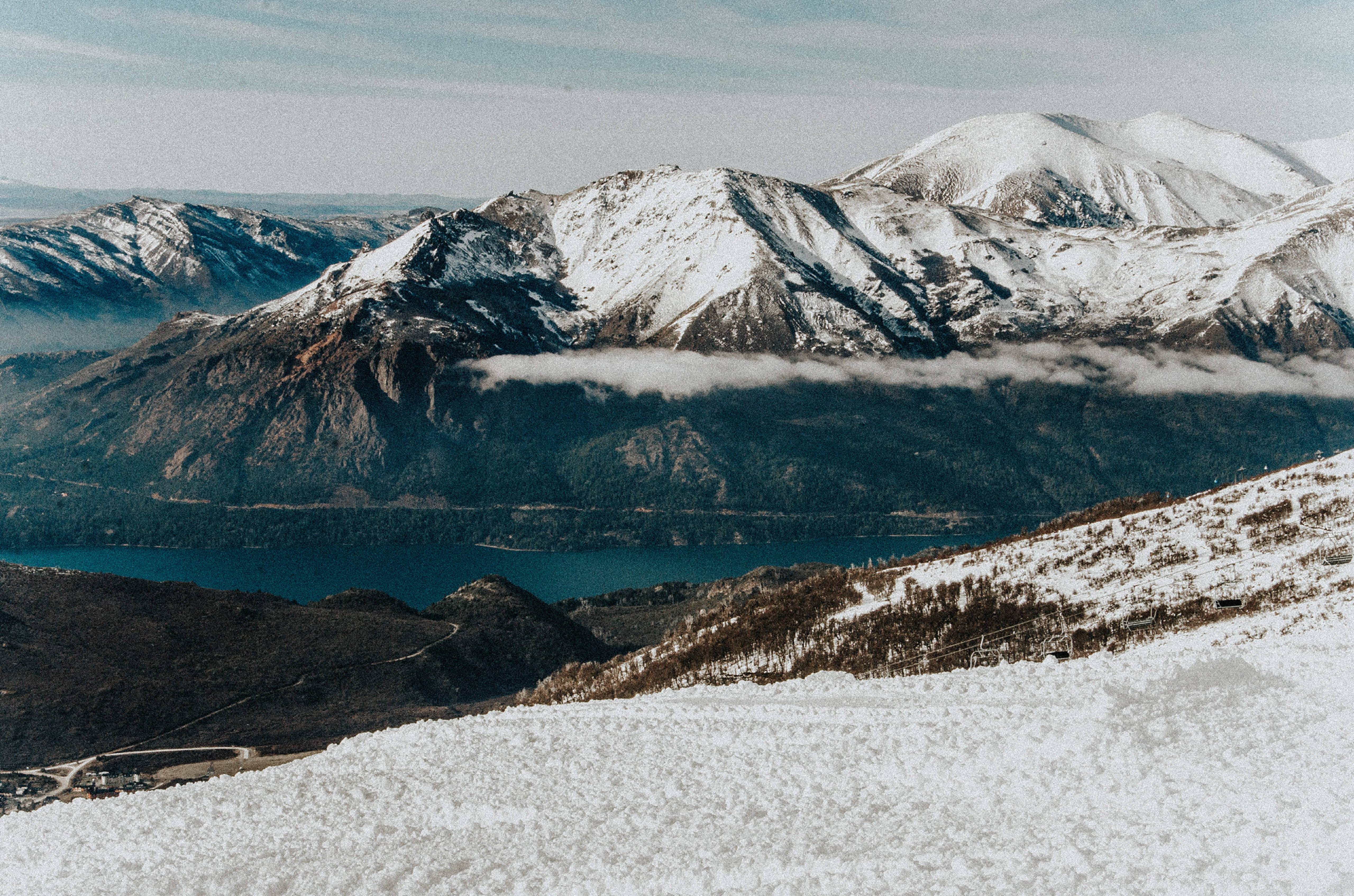 Argentina 桌布 壁紙 — 積雪的山峰在霧氣瀰漫的山谷上方聳立，深藍色的湖泊坐落於崎嶇的山峰之間。