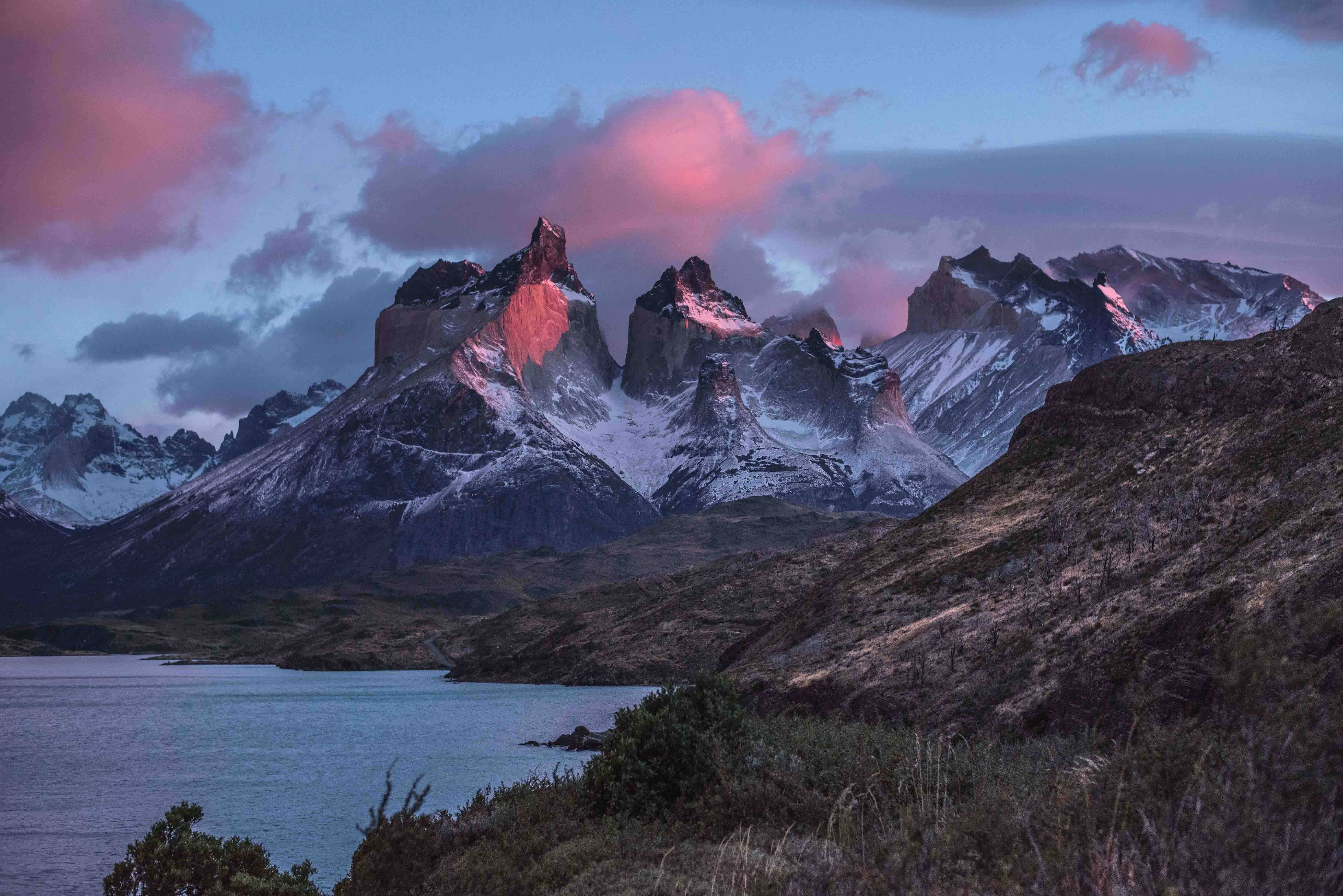South America 桌布 壁紙 — 積雪的山峰在黃昏時分，在暮色天空下，在平靜的湖面上閃耀著粉紅色的光芒。