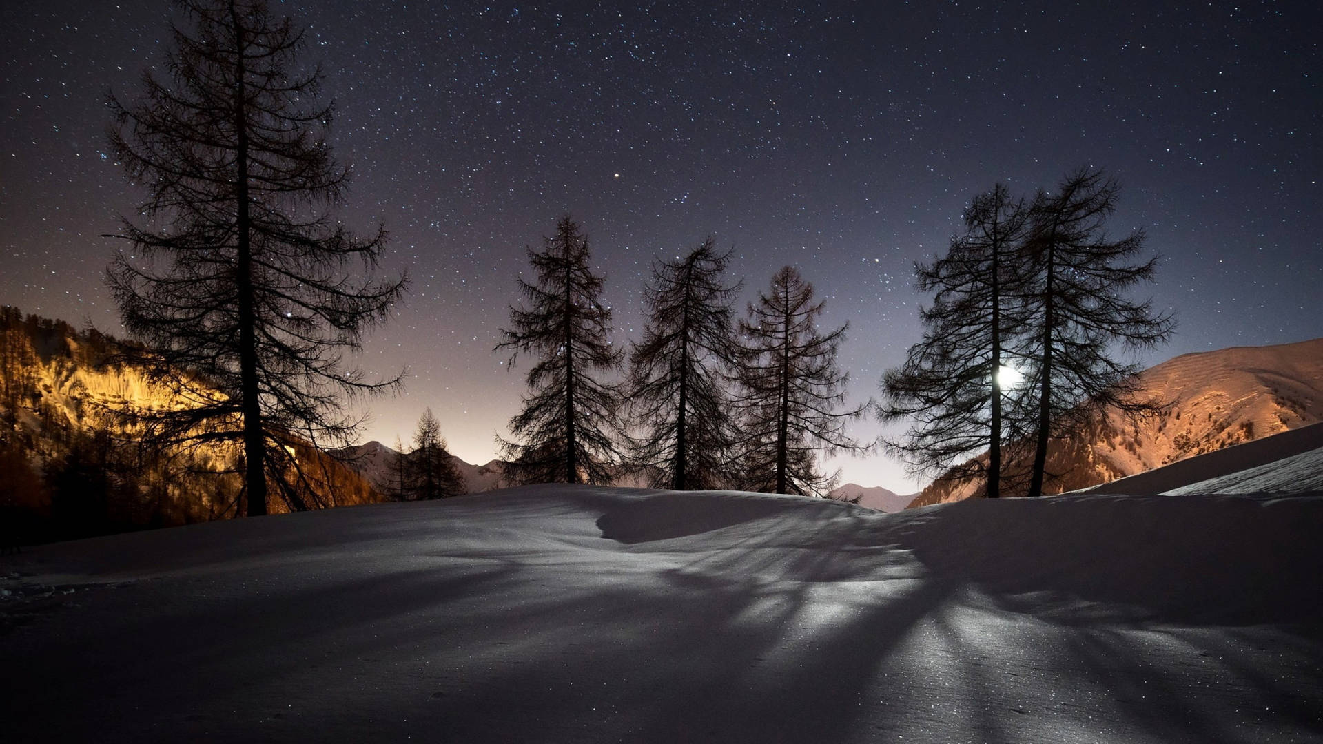 積雪的山脊與松樹在星空下，以及發光的月亮。 — Google Meet 壁紙