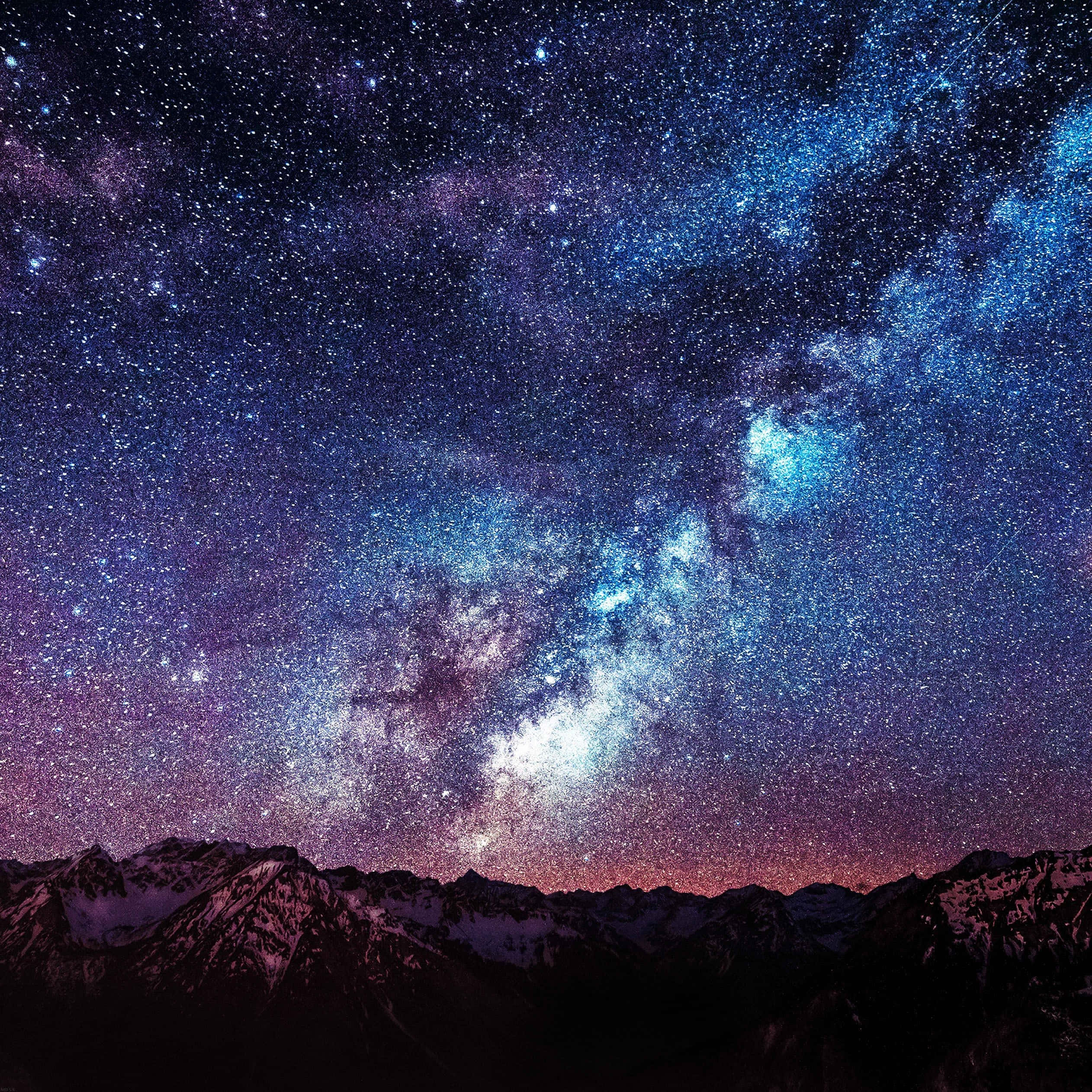 夜空 桌布 壁紙 — 積雪覆蓋的山脈在充滿發光藍色和紫色星雲及銀河系的生動星空下升起。