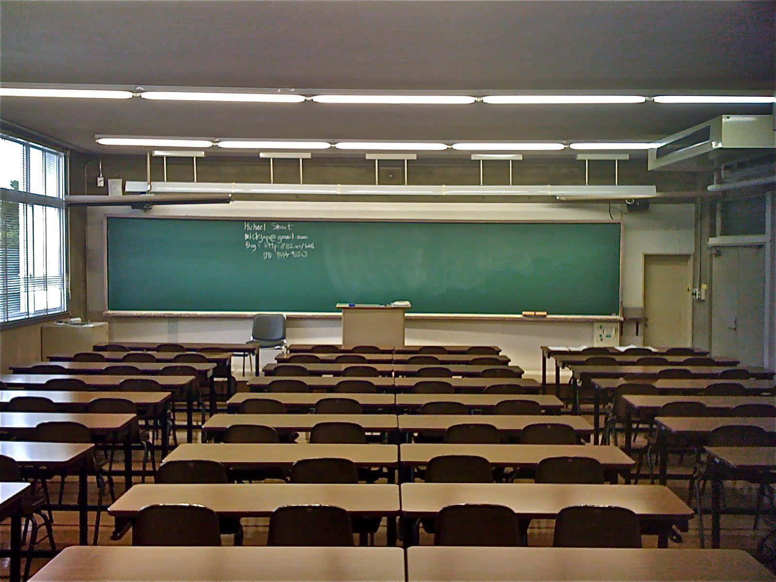 Real Classroom 桌布 壁紙 — 空無一人的教室，木製書桌和椅子排成行，面向綠色黑板，上方是螢光燈。