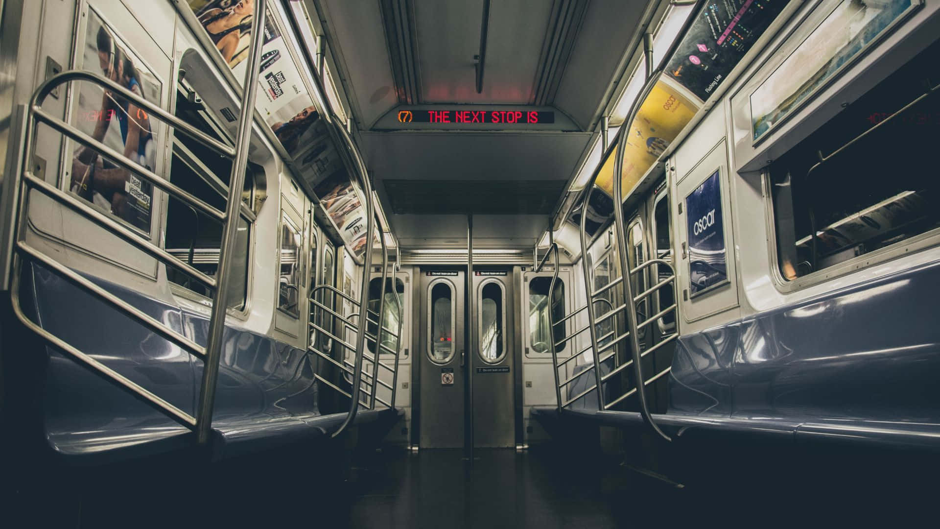 Subway 桌布 壁紙 — 空置地鐵車廂內部，設有金屬柱、廣告及顯示下一站的紅色電子顯示屏