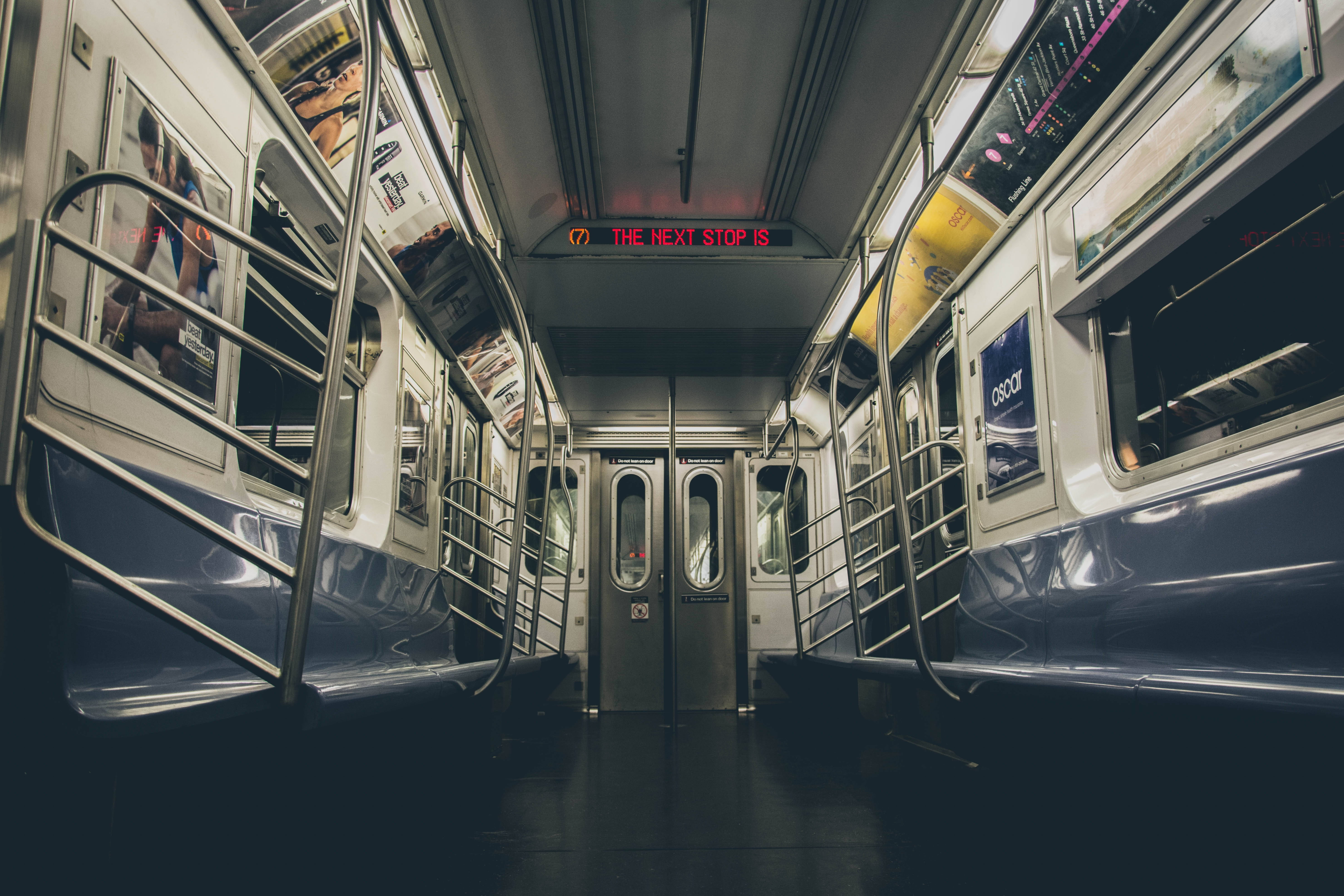 Subway 桌布 壁紙 — 空置的地鐵車廂內部，設有金屬柱和發光的紅色數位顯示屏，顯示下一站資訊。
