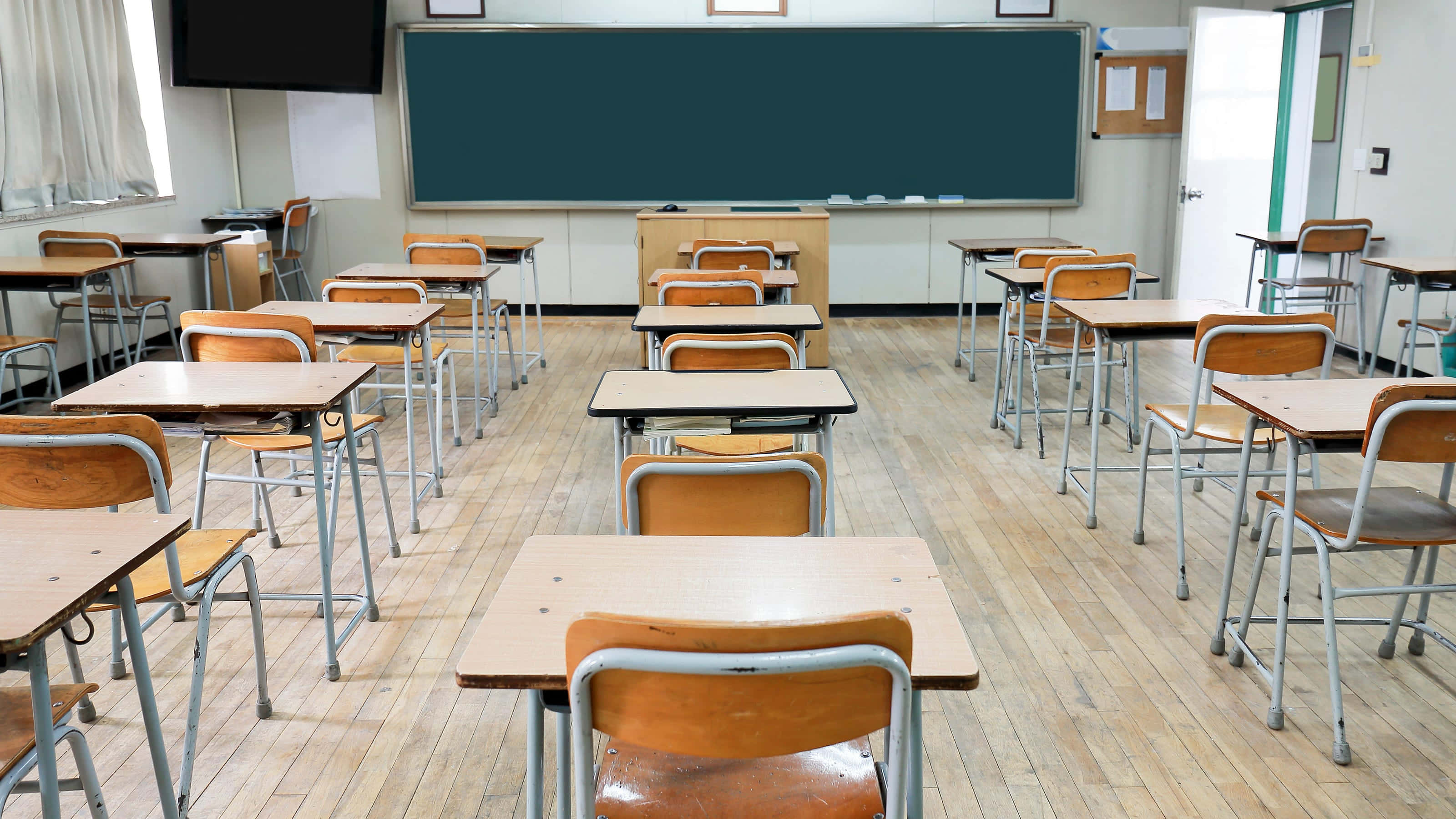 Classroom 桌布 壁紙 — 空置的小學教室，配有木製桌椅和綠色黑板，在明亮的螢光燈下。
