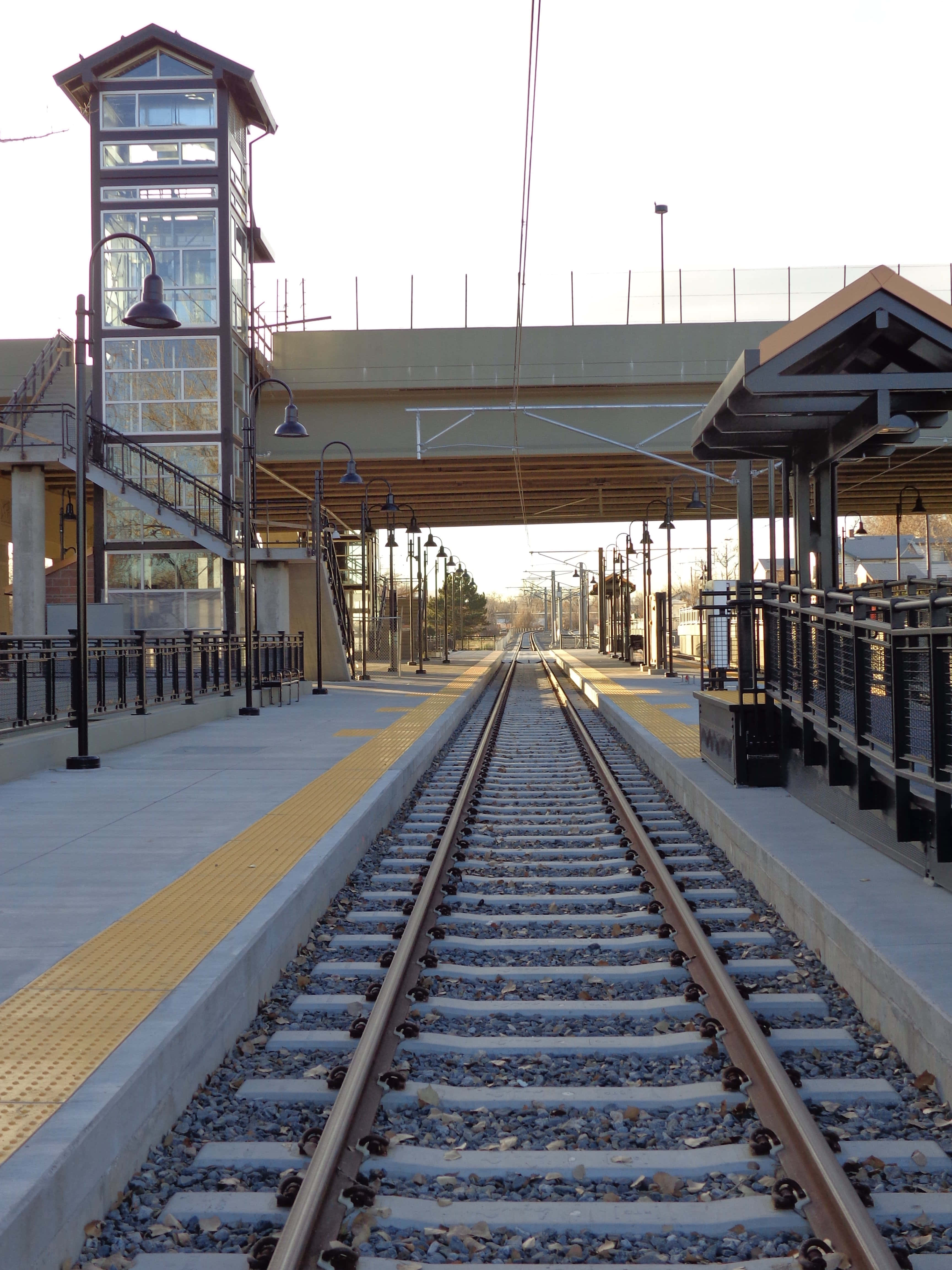 Train Station 桌布 壁紙 — 空蕩的火車站月台，鐵軌在晴朗的天空下延伸至遠方。