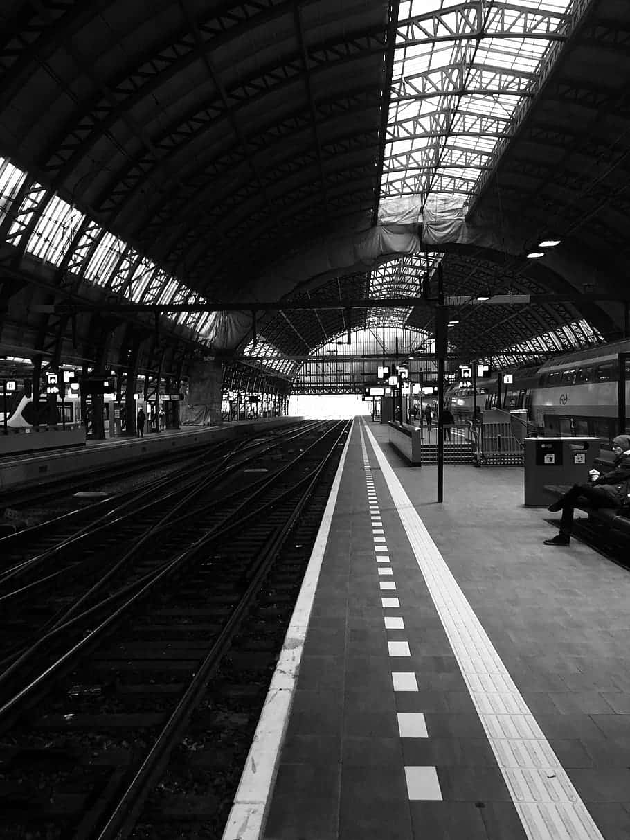 Aesthetic Black And White 桌布 壁紙 — 空蕩的火車站月台黑白景觀，軌道延伸至明亮遙遠的隧道。