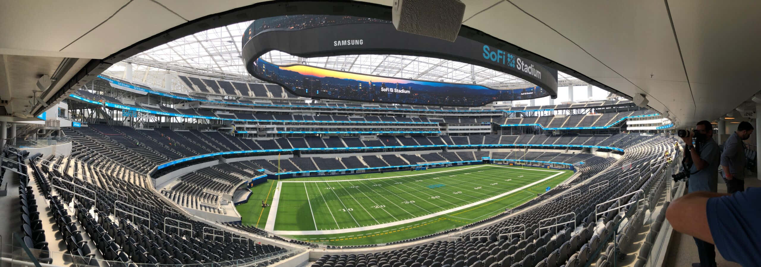 Sofi Stadium 桌布 壁紙 — 空蕩蕩的SoFi體育場全景，綠色球場和分層座位在玻璃屋頂下。