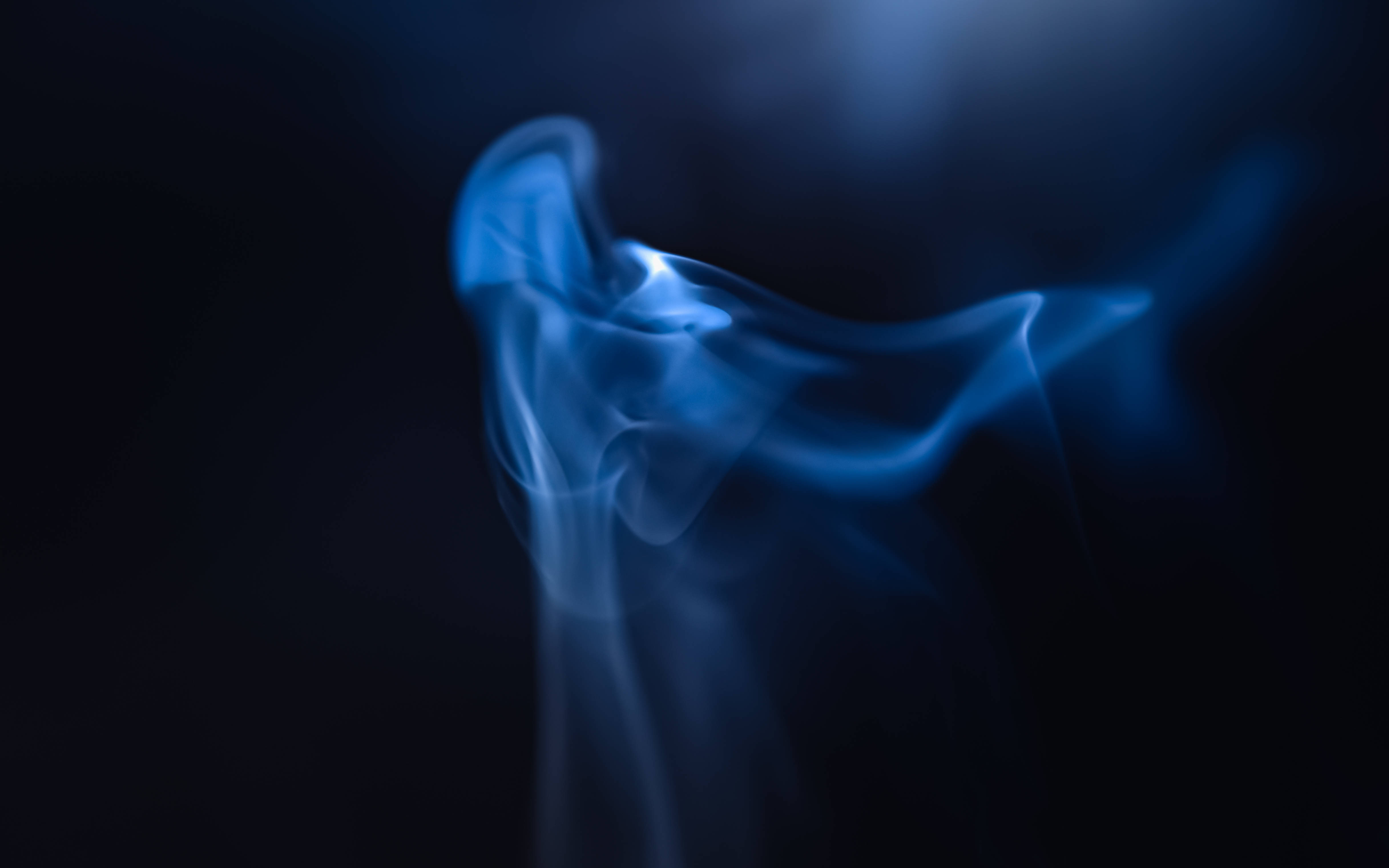 藍色抽象 桌布 壁紙 — 空靈的藍色煙霧在深黑色背景上優雅地盤旋，營造出神秘而平靜的視覺效果。
