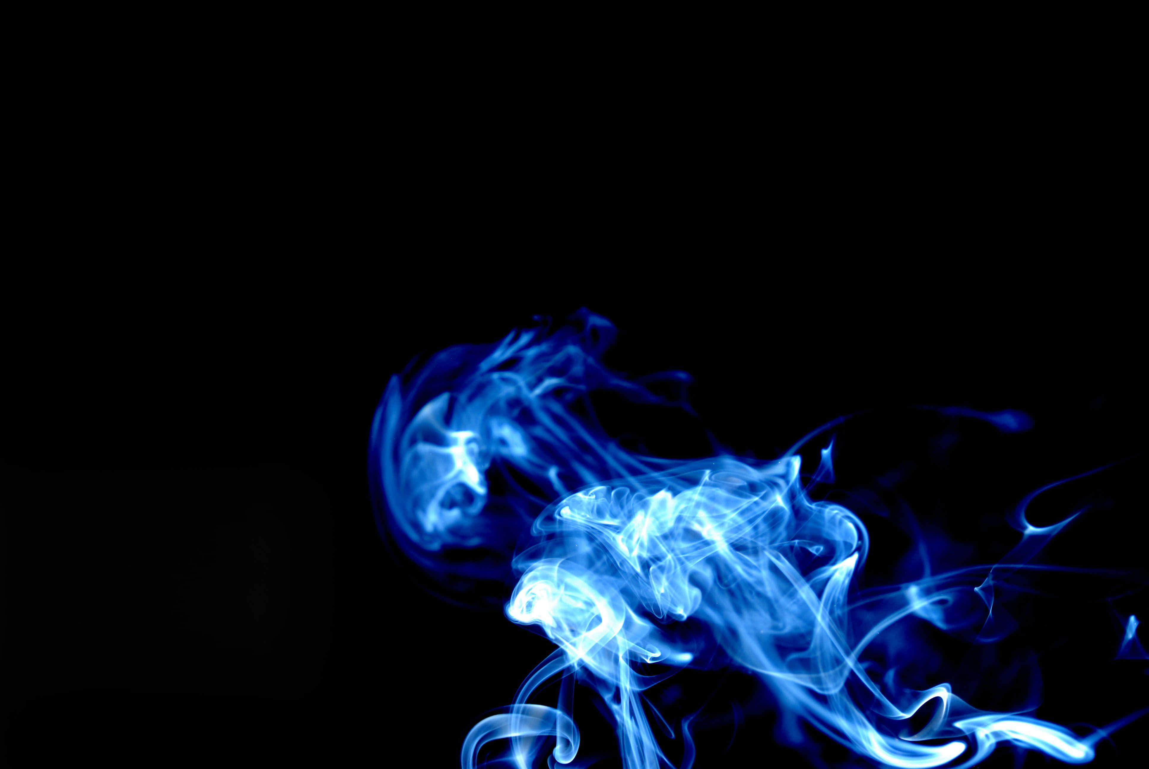 Smoke Blue 桌布 壁紙 — 空靈的藍色煙霧在純黑色背景上優雅地旋轉，營造出迷人的抽象動感。