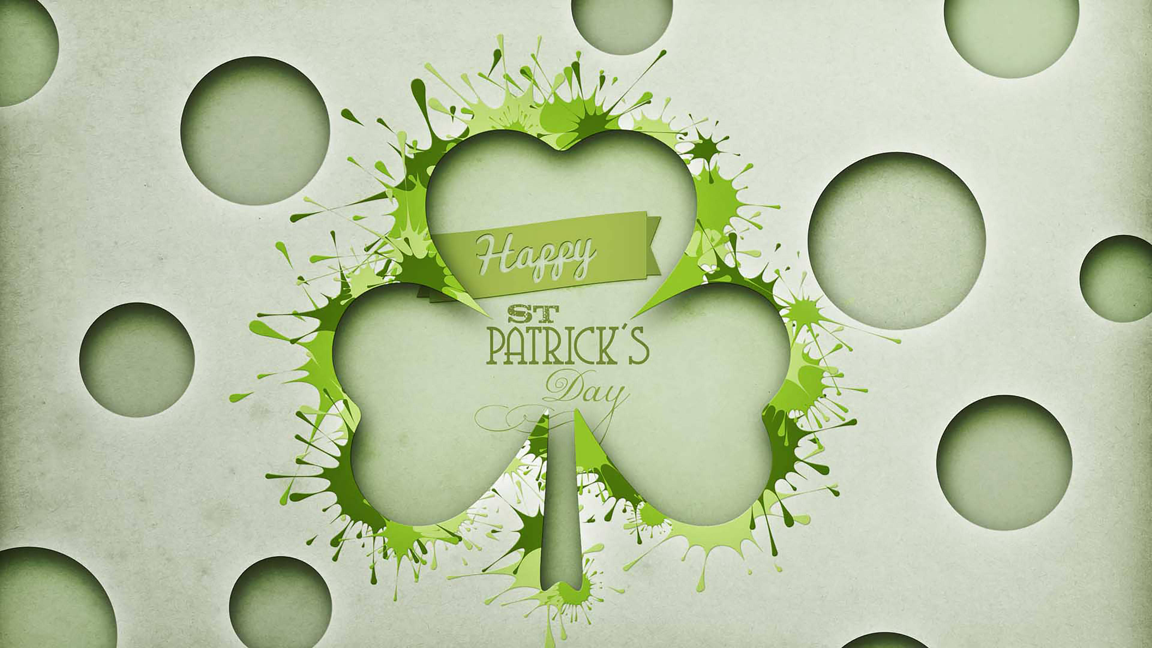 Happy St Patricks Day 桌布 壁紙 — 穿孔紙背景上帶有潑濺效果和「Happy St Patrick's Day」文字的節日綠色三葉草。