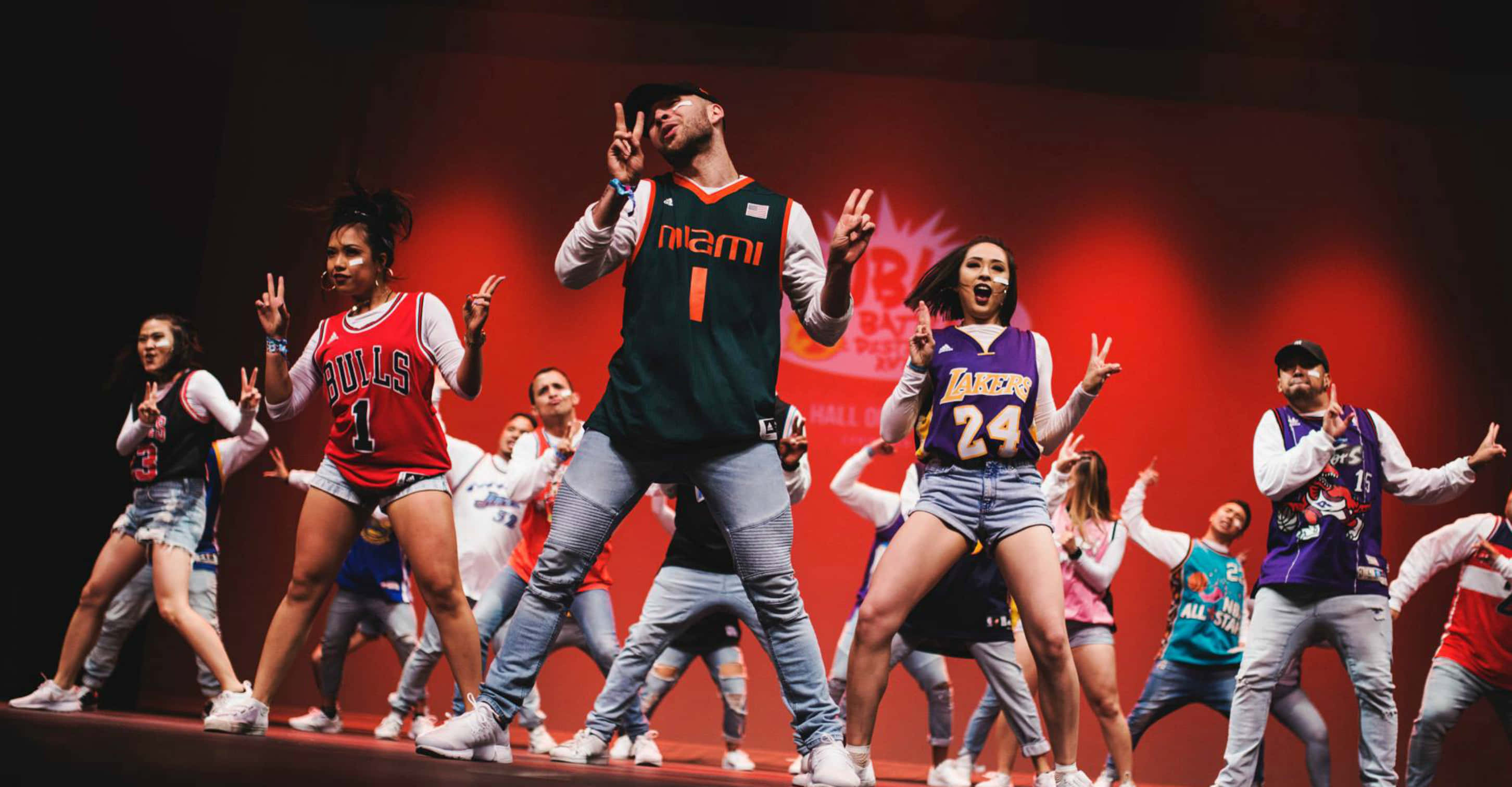 hiphop 桌布 壁紙 — 穿著NBA球衣服裝的舞者在紅色燈光的舞台上，在充滿活力的表演中擺出充滿活力的姿勢。