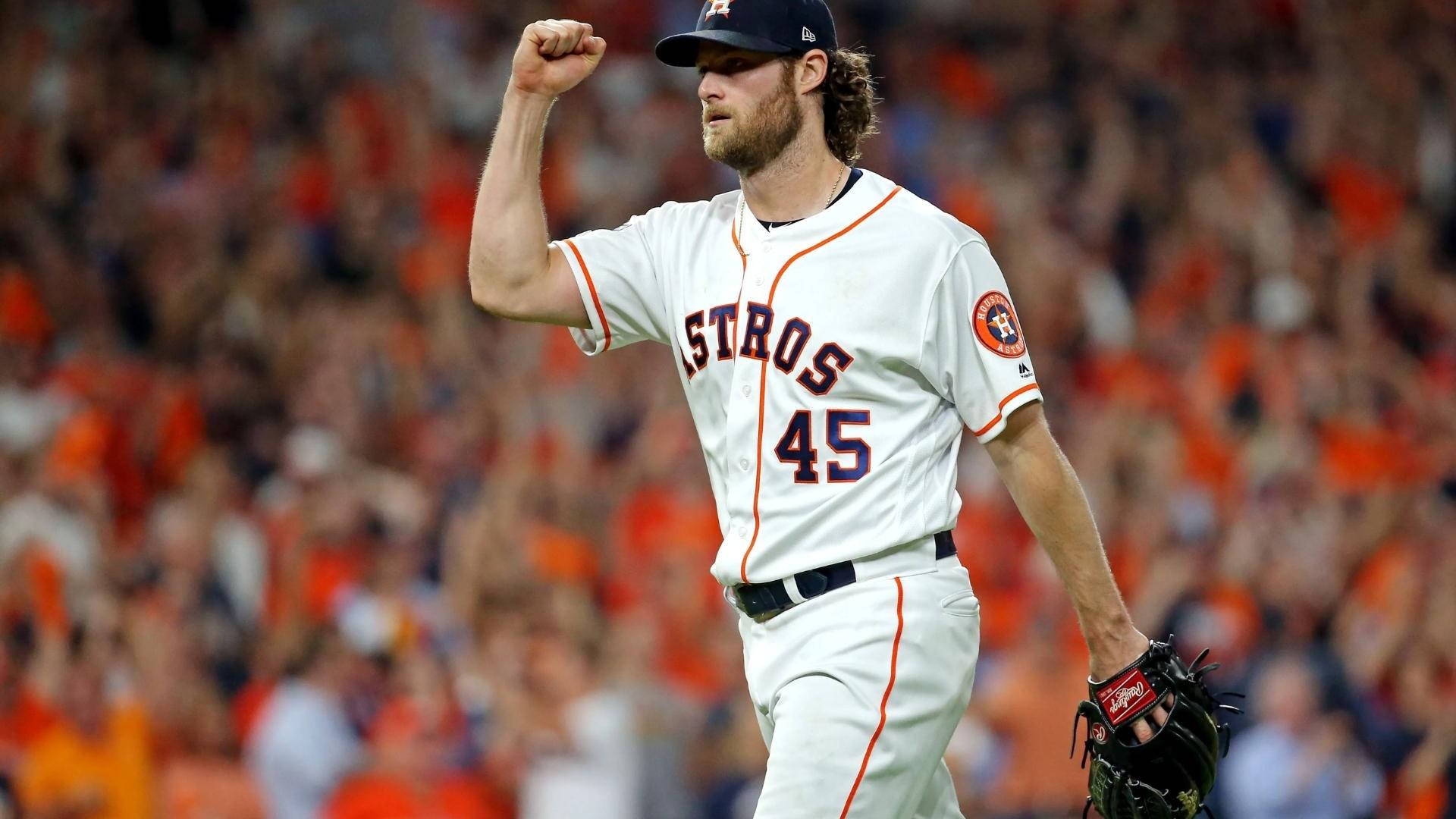 Gerrit Cole 桌布 壁紙 — 穿著太空人隊球衣的棒球選手在球場上握拳慶祝勝利，背景是模糊的橙色人群。