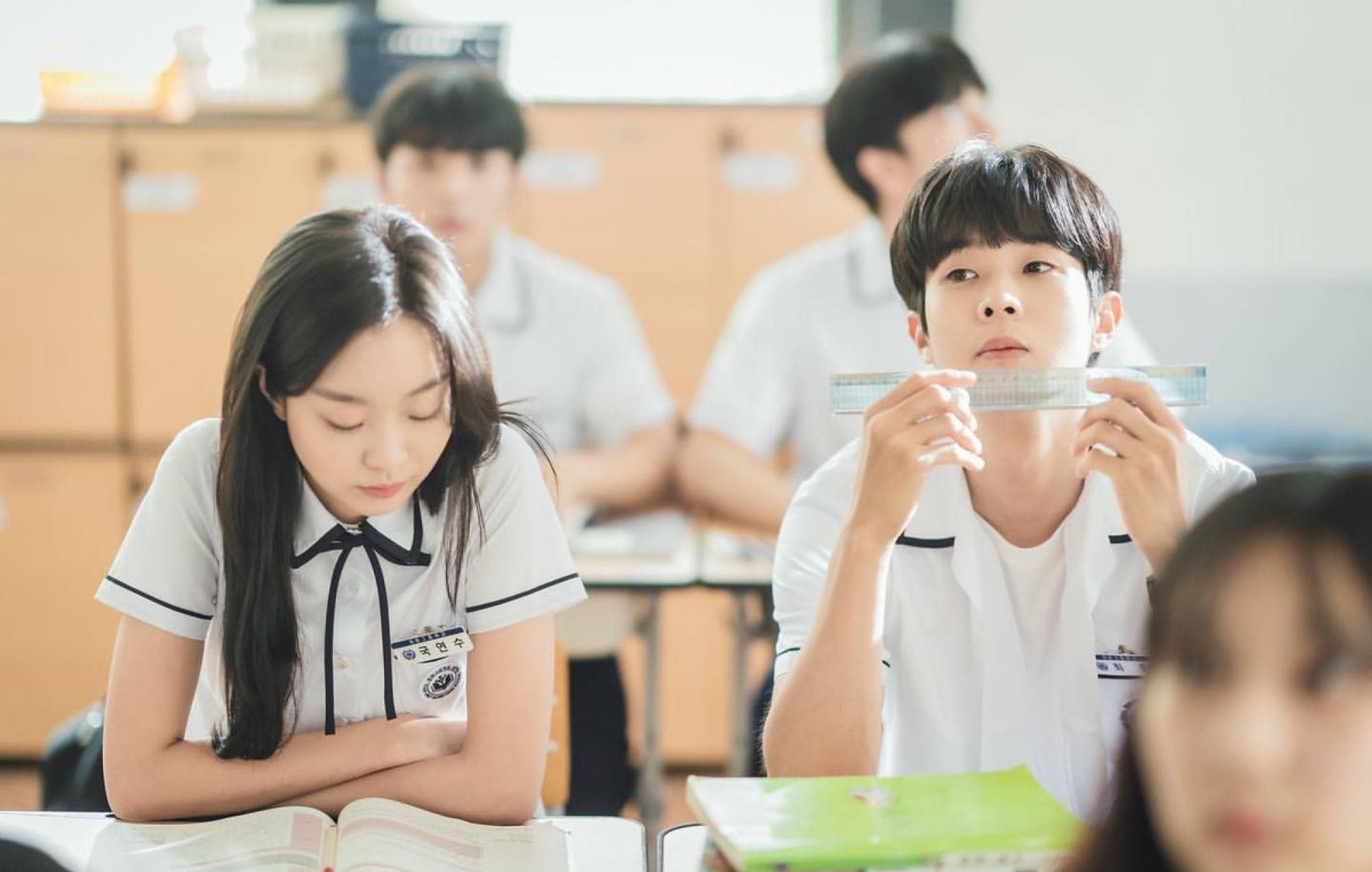 Beloved 桌布 壁紙 — 穿著校服的學生坐在明亮的教室裡。一個女孩低頭，而一個男孩把尺子舉到臉前。