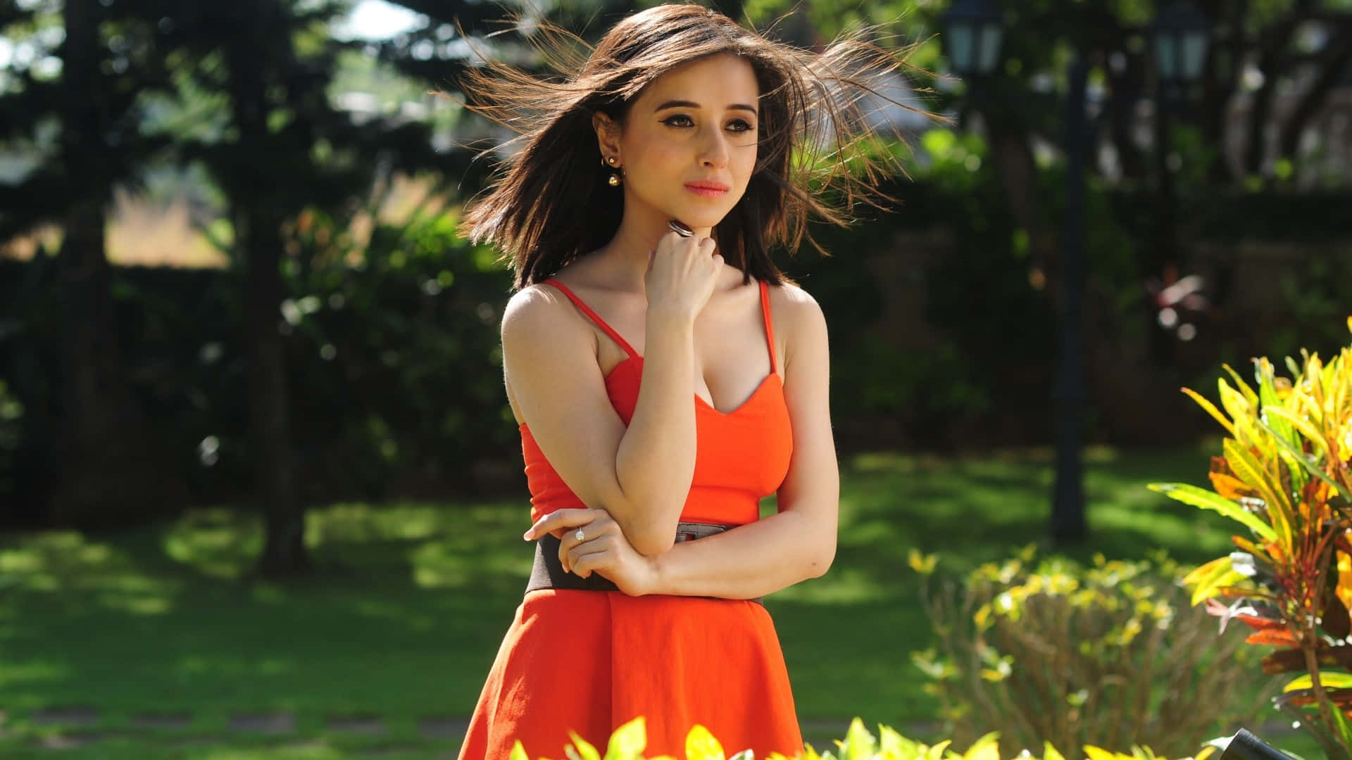 穿著橘色洋裝的美麗女子在公園中擺姿勢 壁紙