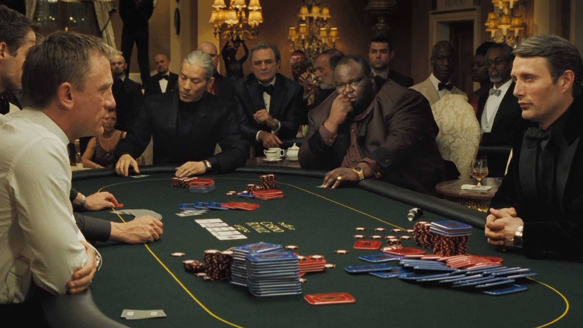 Poker 桌布 壁紙 — 穿著正式服裝的男士在豪華賭場房間的水晶吊燈下，於綠色絨毛桌上激烈地玩撲克。