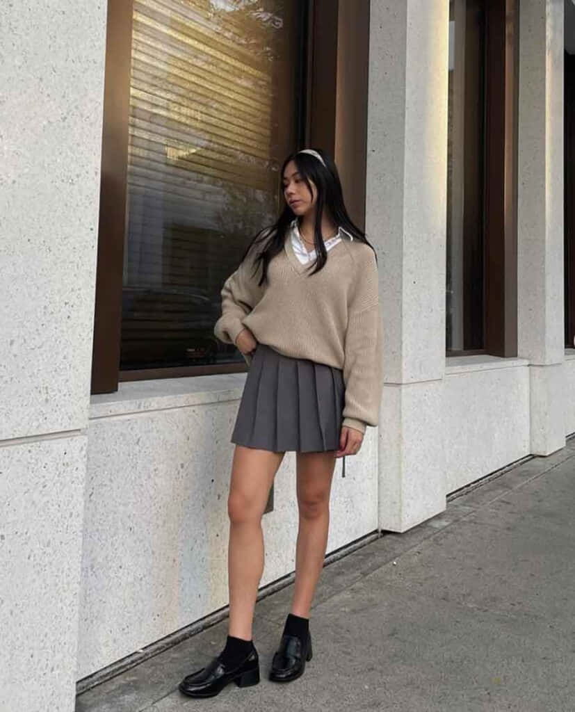穿著毛衣與裙子倚牆而立的女子 壁紙