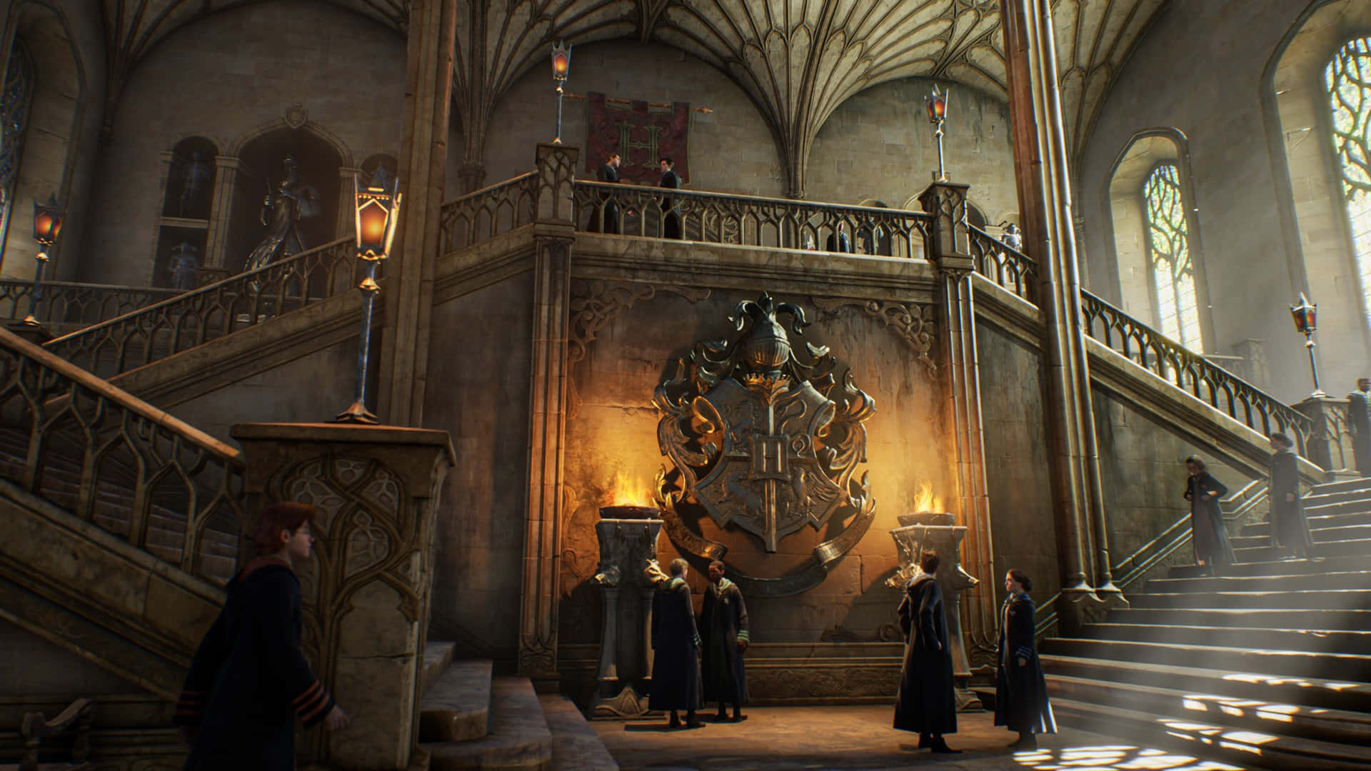 Christmas At Hogwarts 桌布 壁紙 — 穿著深色長袍的學生們站在霍格華茲大禮堂的宏偉樓梯和徽章前，溫暖的燈光映照著。