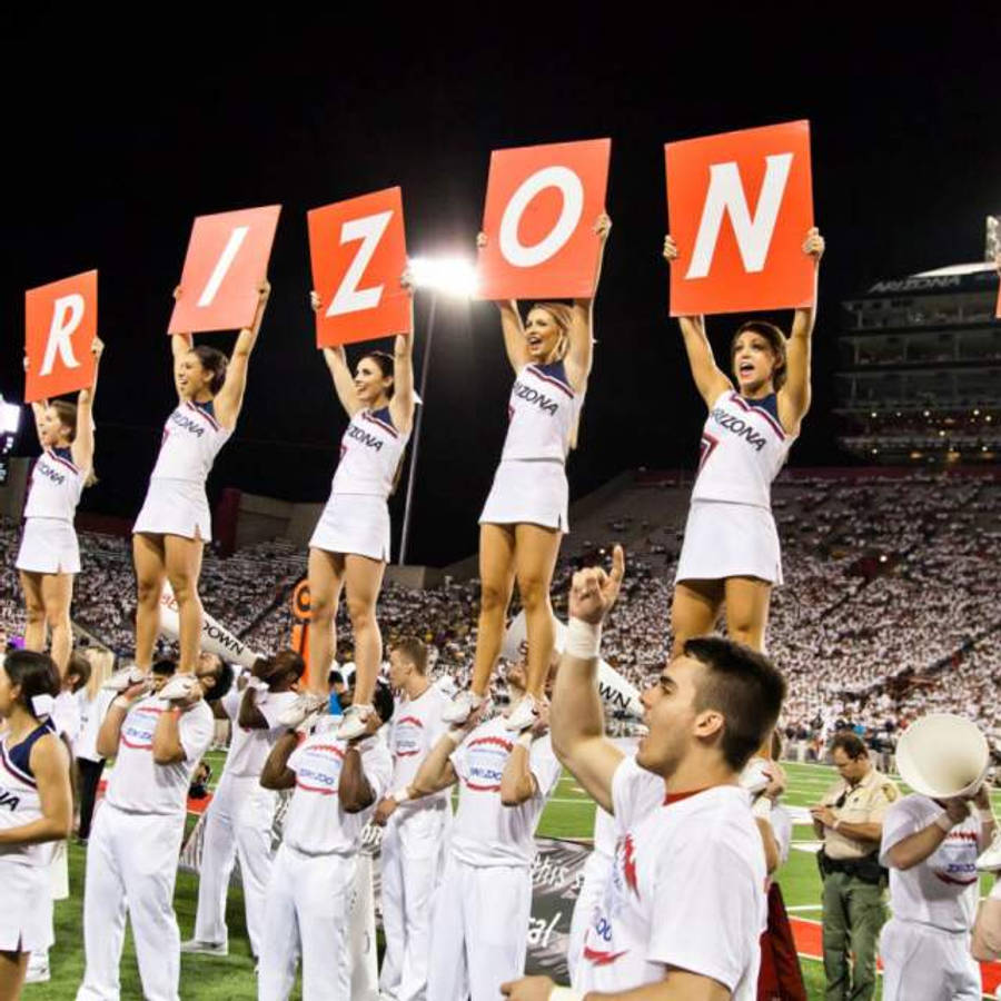 Cheerleader 桌布 壁紙 — 穿著白色制服的啦啦隊在夜晚形成人體金字塔，在球場燈光下舉著紅色標牌拼出ARIZONA。