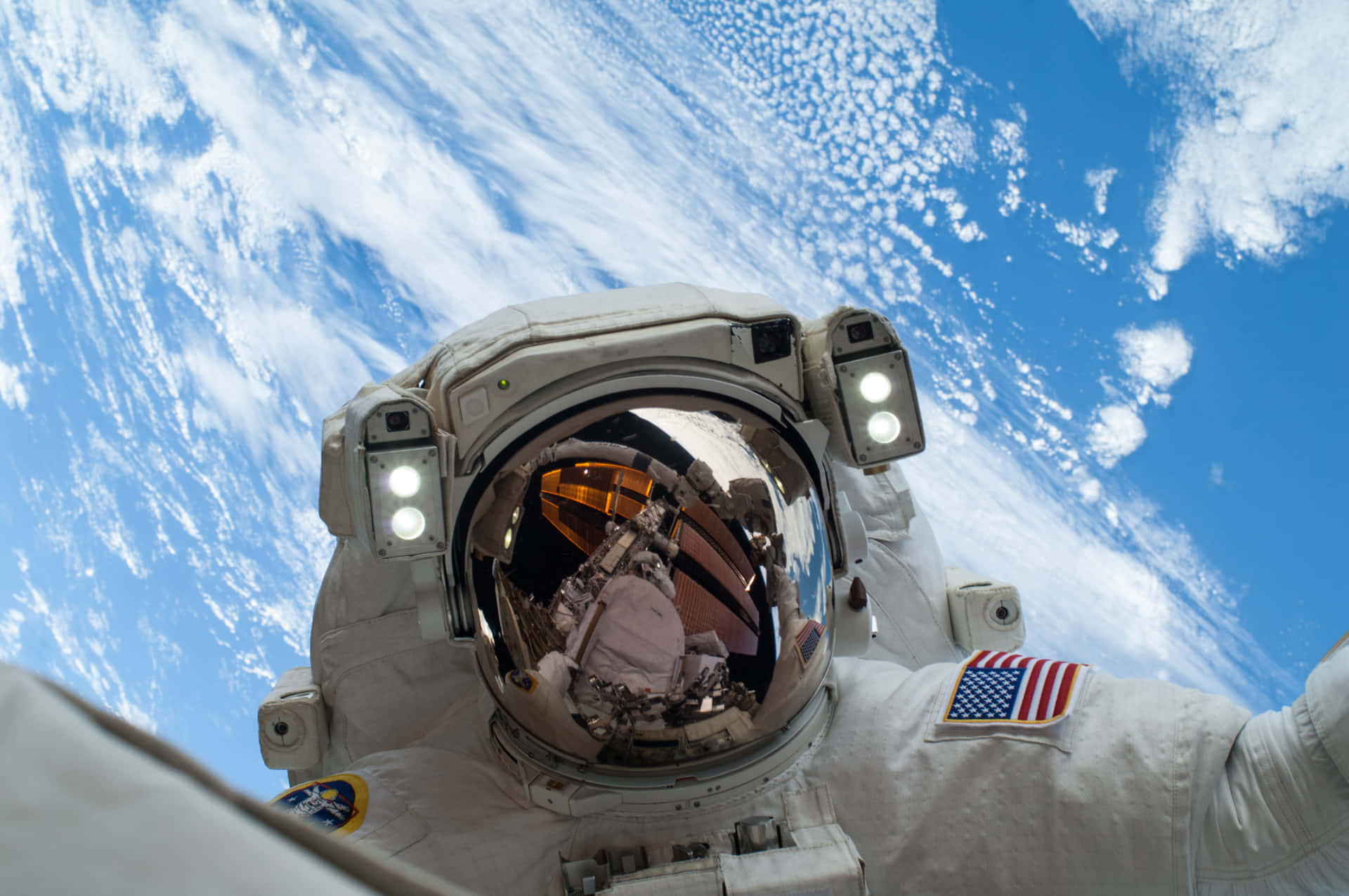  壁紙 — 穿著白色太空衣的太空人漂浮在地球上空，透過頭盔面罩可以看到藍色的海洋和白色的雲層。