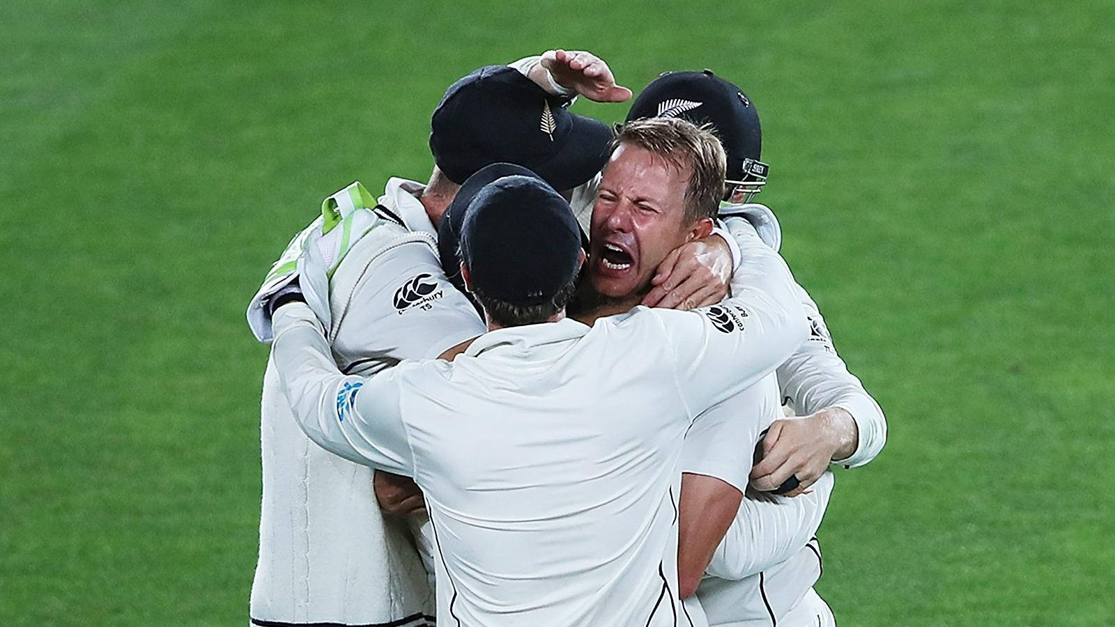 kane williamson 桌布 壁紙 — 穿著白色球衣的板球運動員在體育場燈光下，於充滿活力的綠色場地上熱情擁抱。