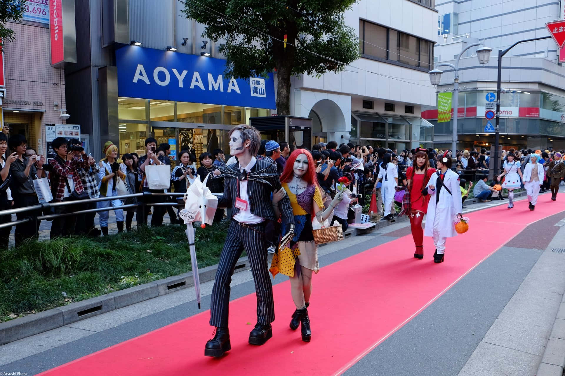 Halloween Parades 桌布 壁紙 — 穿著精緻服裝的角色扮演者在熱鬧的會議期間，在繁華的城市街道上的紅地毯上遊行。