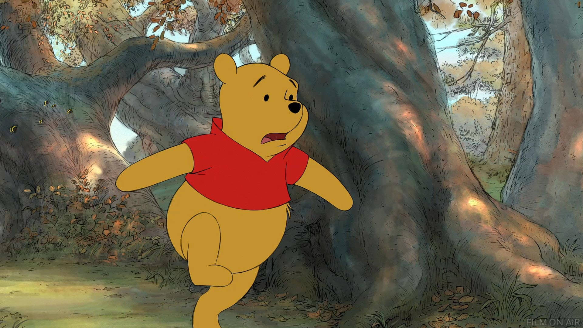 winnie the pooh 桌布 壁紙 — 穿著紅色襯衫的小熊維尼在陽光明媚、有巨大樹木和落葉的森林中快樂地奔跑。