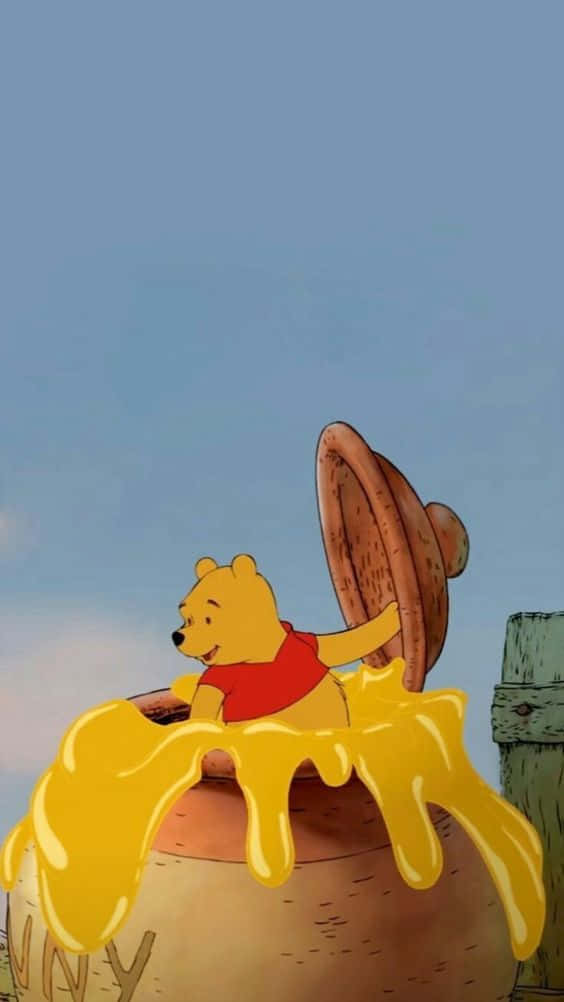 winnie the pooh 桌布 壁紙 — 穿著紅色襯衫的小熊維尼快樂地坐在一個巨大的蜂蜜罐上，蜂蜜滴落下來，背景是清澈的藍天。