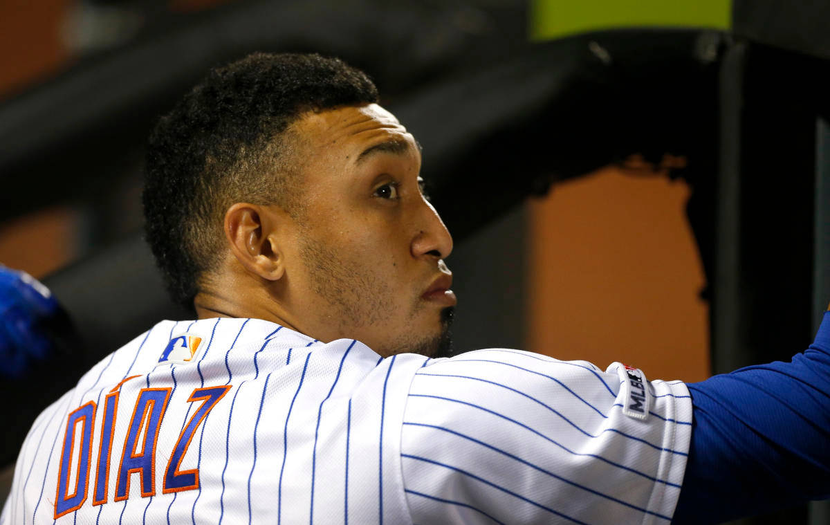 MLB 桌布 壁紙 — 穿著細條紋球衣的棒球運動員Diaz在體育場燈光下比賽時，身體前傾，神情專注。